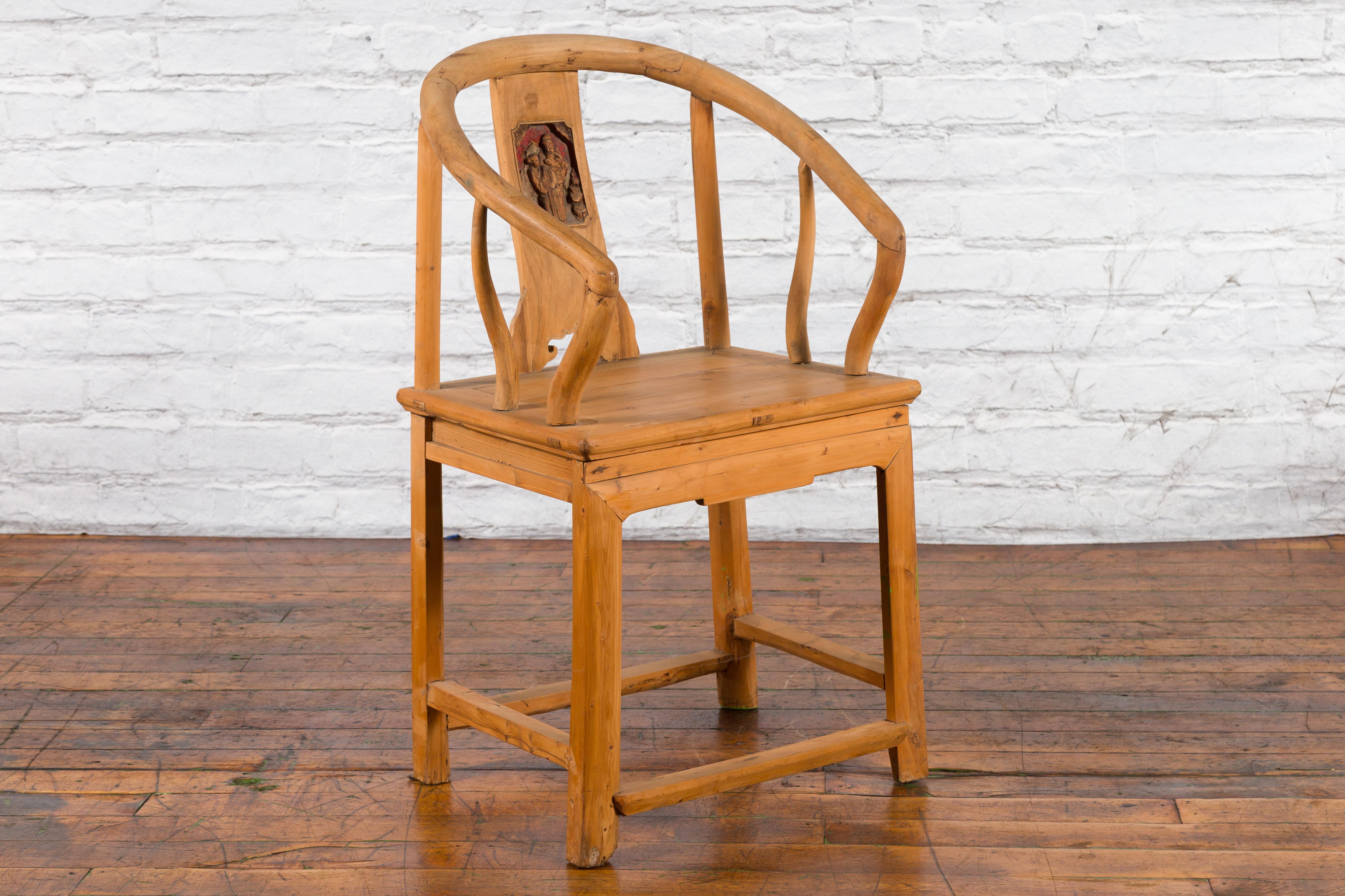 A Chinese Qing Dynasty period elmwood horseshoe back chair from the 19th century, with hand-carved medallion and natural patina. Created in China during the Qing Dynasty, this elmwood chair features a horseshoe back carved with characters standing