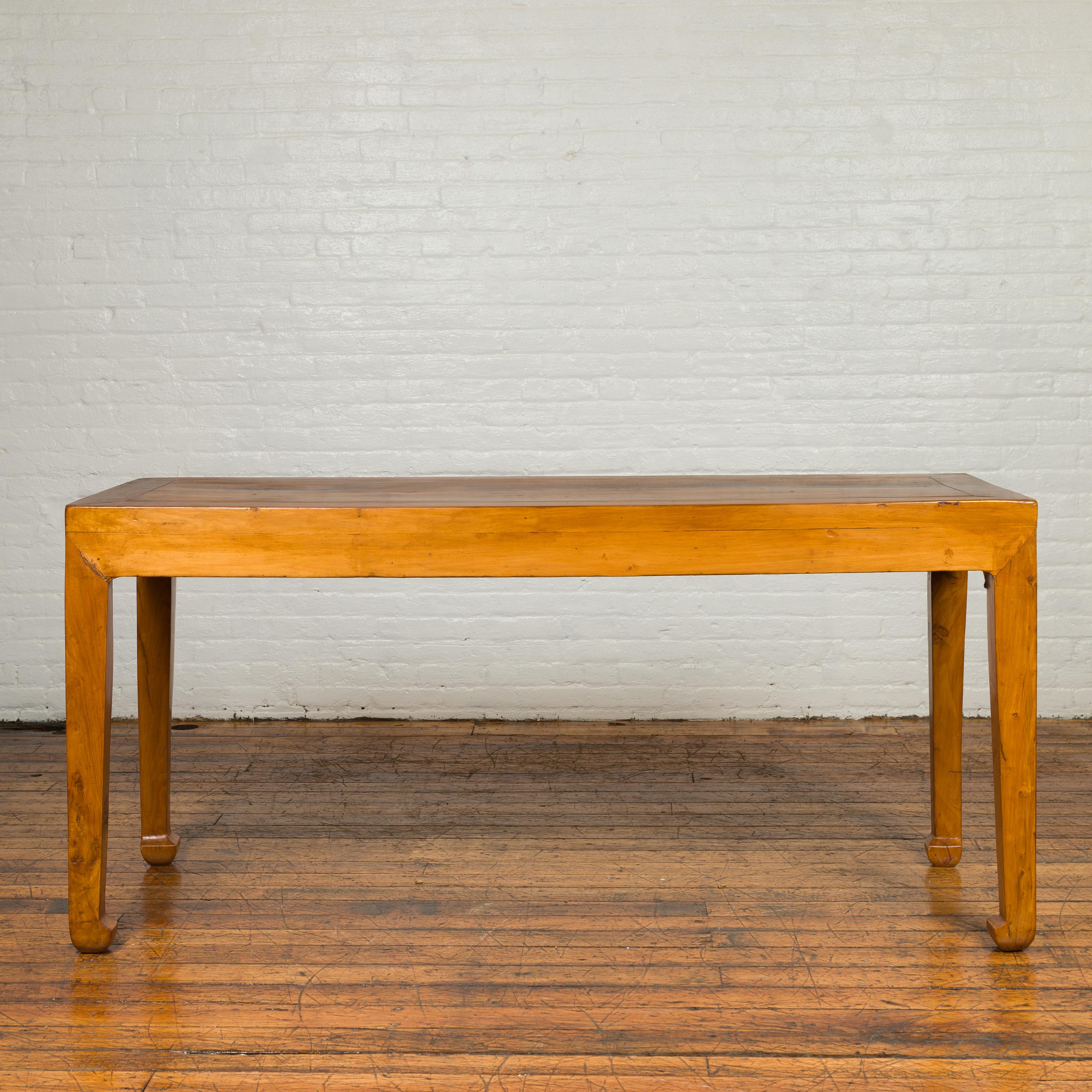 A Chinese Qing Dynasty elmwood console table with distressed patina and horsehoof legs. Crafted in China during the Qing Dynasty, this elmwood console table features a rectangular planked top, sitting above four slender legs with horsehoof