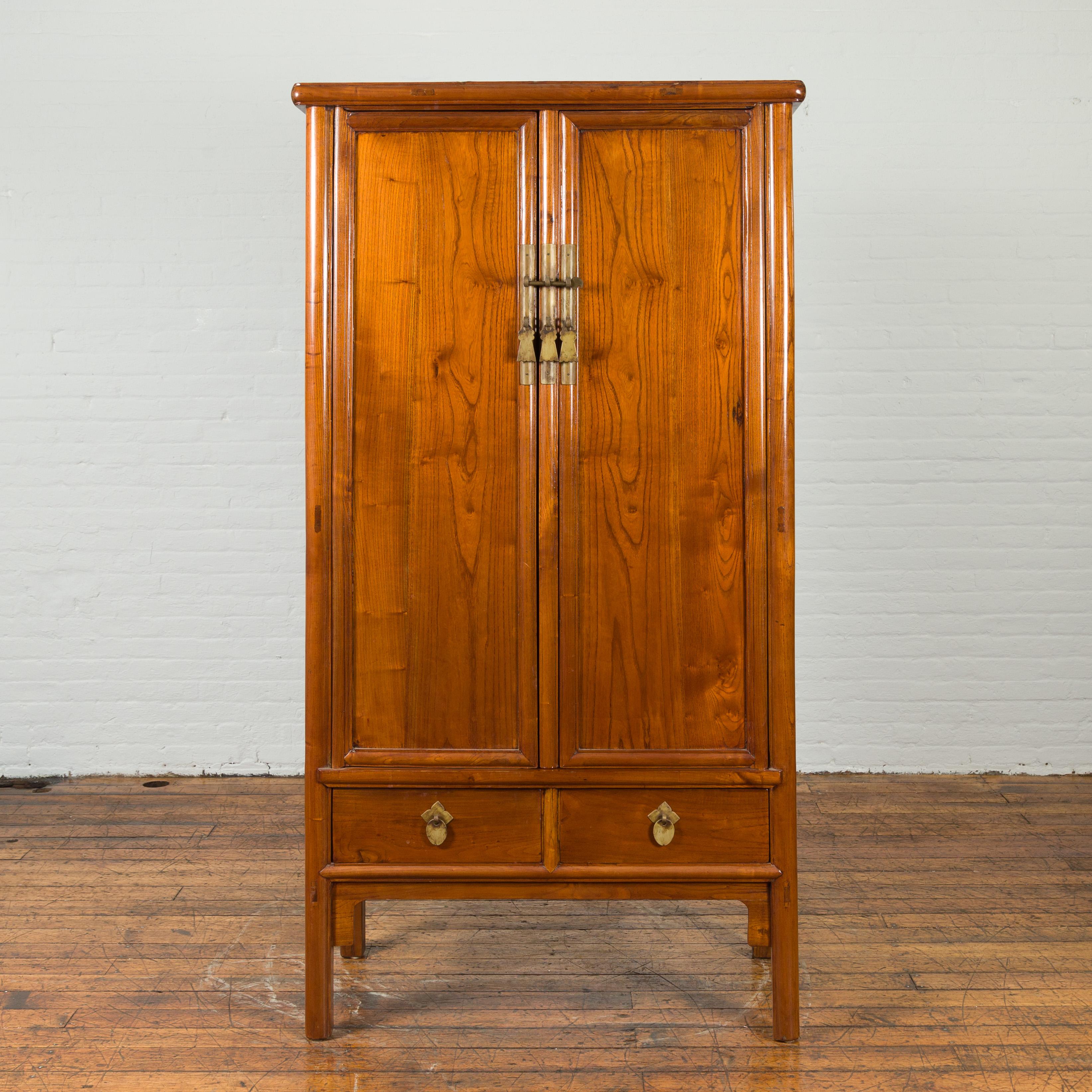 A Chinese Qing dynasty period natural elm noodle cabinet from the 19th century, with brass hardware and drawers. Created in China during the Qing dynasty, this elm cabinet features a tapering silhouette accented with brass hardware. The two doors