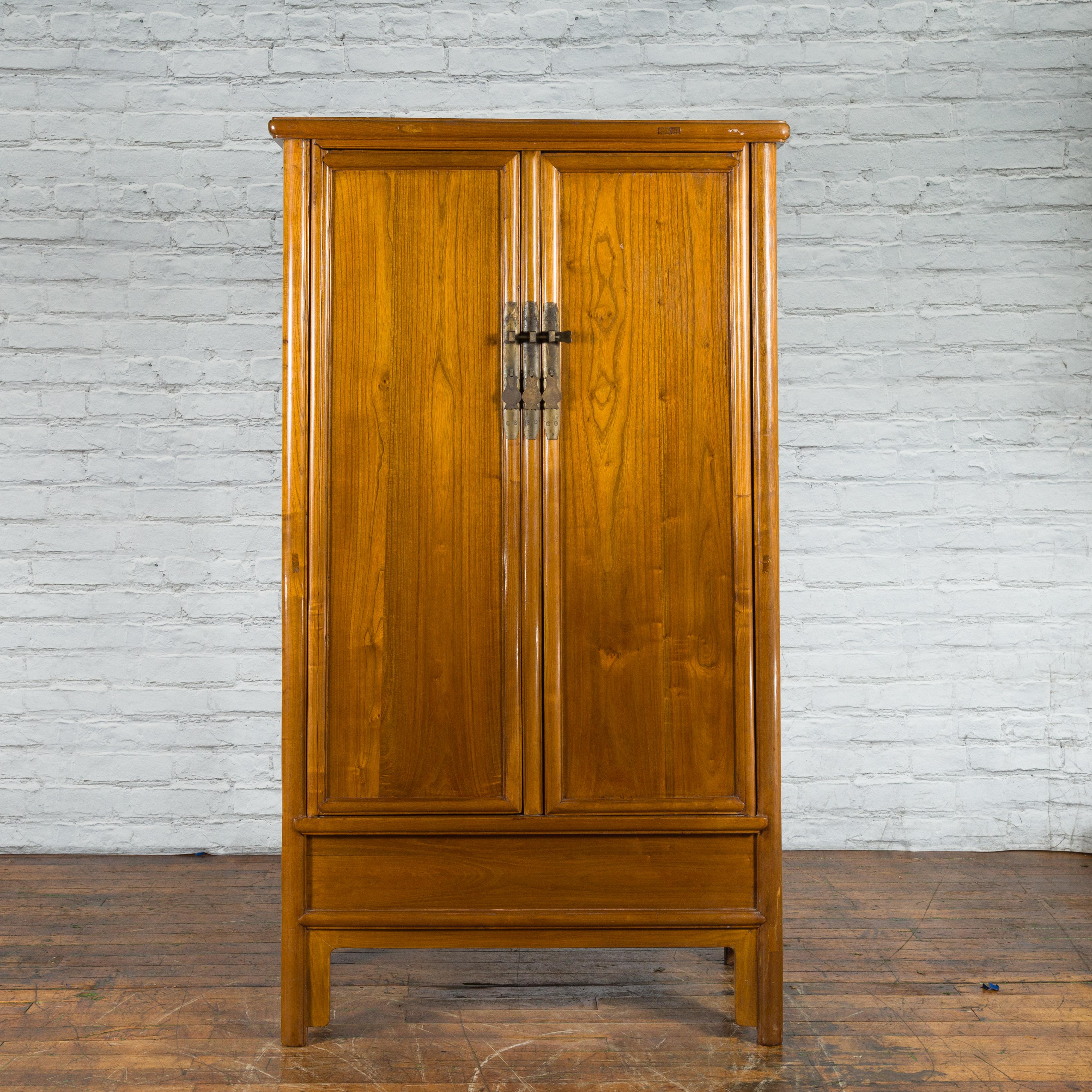 A Chinese Qing Dynasty period elm wood noodle cabinet from the 19th century, with brass hardware, tapering lines and hidden drawers. Created in China during the Qing Dynasty period in the 19th century, this elm wood cabinet draws the attention with