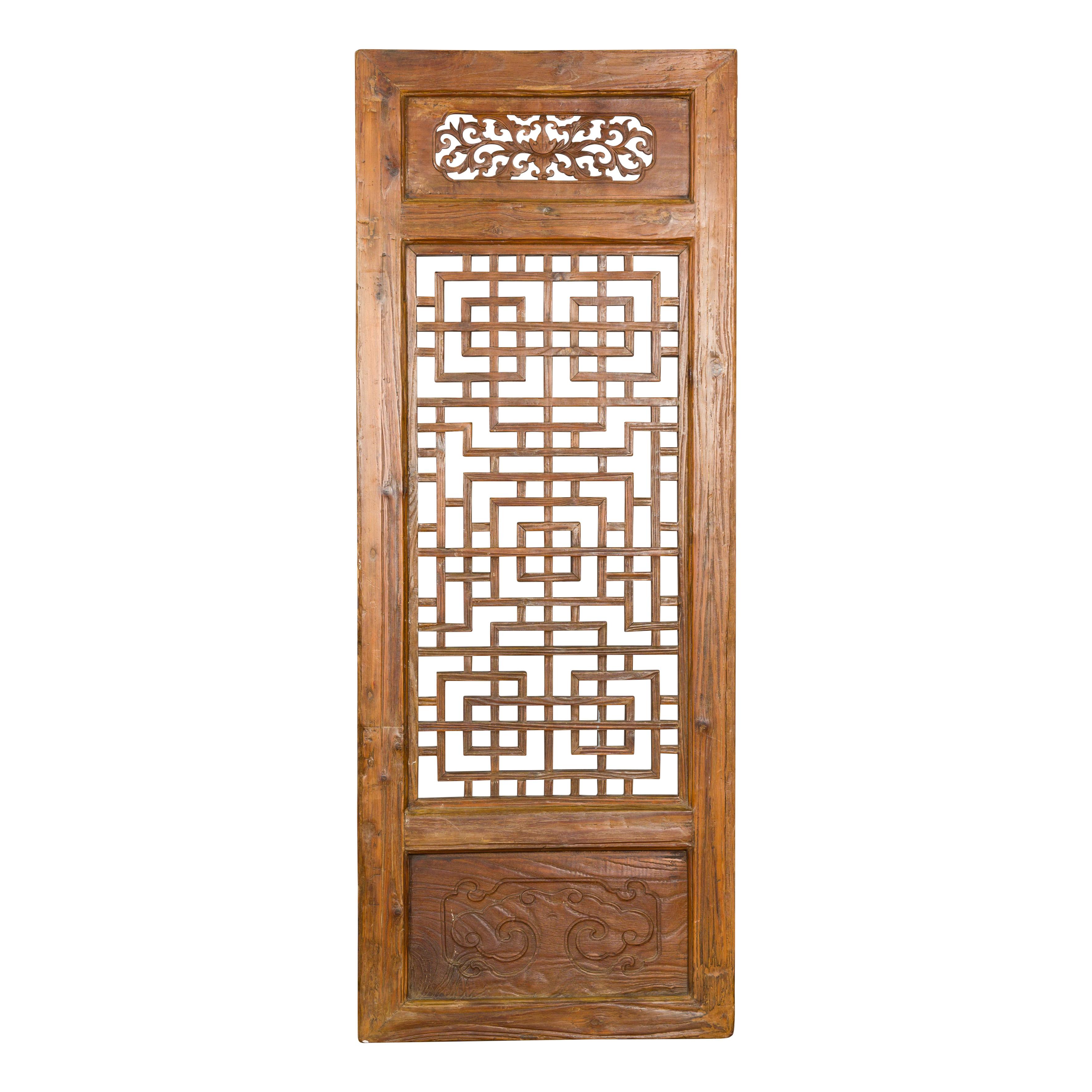 A Chinese Qing Dynasty period wooden screen from the 19th century with fretwork motifs, carved scrolling foliage pierced in the upper section and objects carved in low-relief at the bottom. Indulge in the exquisite craftsmanship of this 19th-century