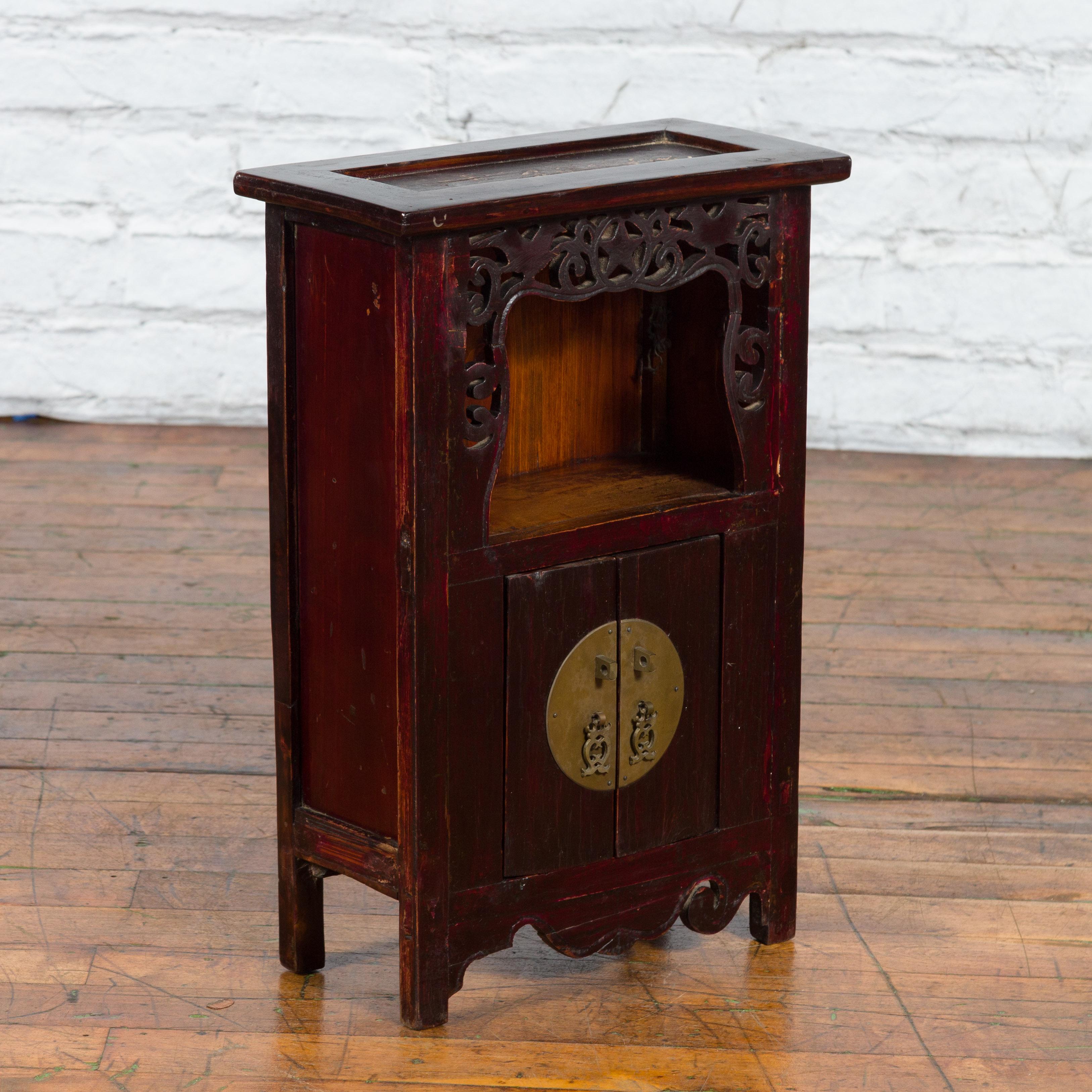 A Chinese Qing Dynasty period jewelry cabinet from the 19th century with star-carved open shelf, double doors, large brass medallion lock and carved apron. Created in China during the Qing Dynasty period in the 19th century, this jewelry cabinet