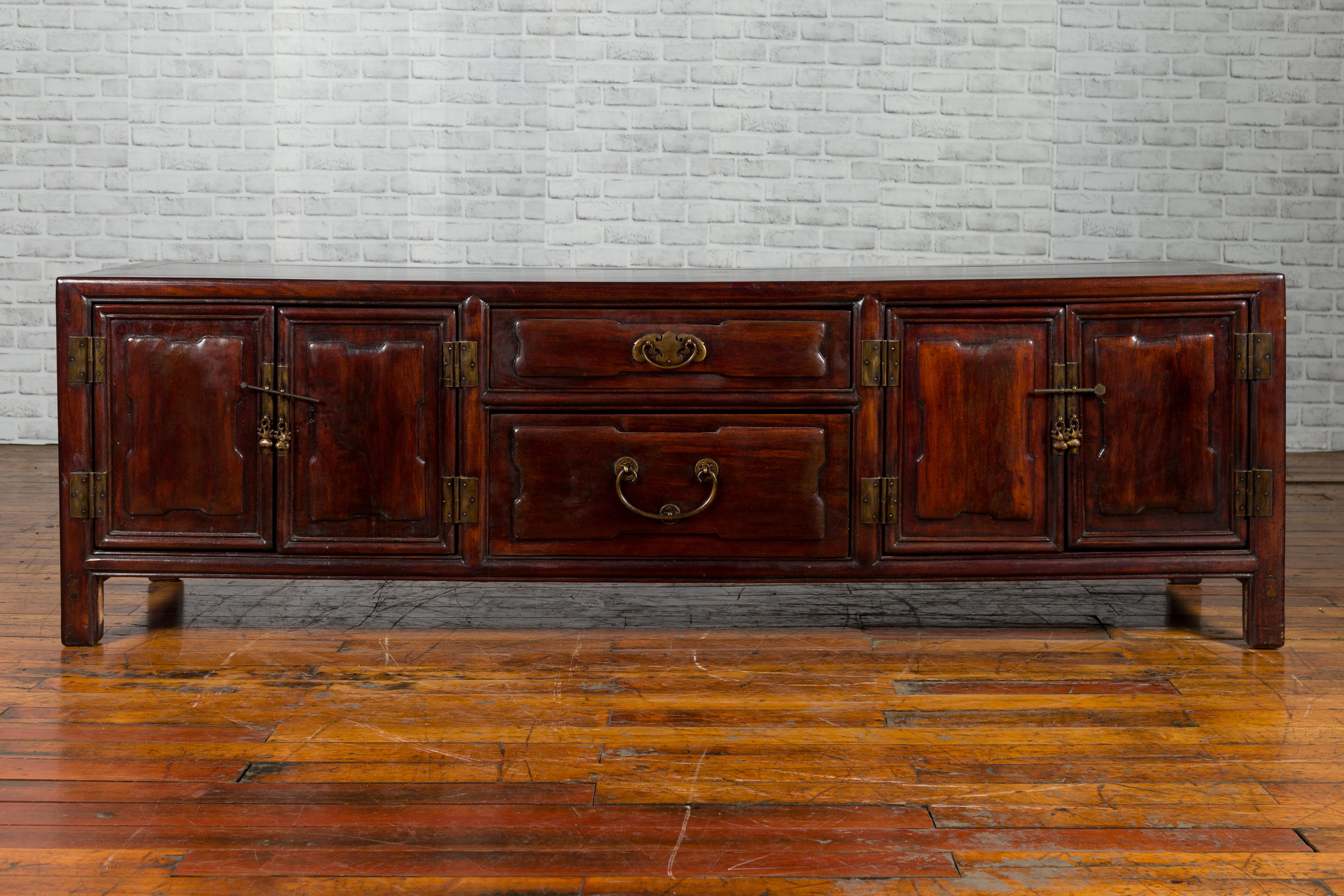 A Chinese Qing Dynasty period low Kang cabinet from the 19th century, with two pairs of double doors and central drawers. Created in China during the 19th century, this Kang cabinet features a long rectangular top with central board, sitting above a