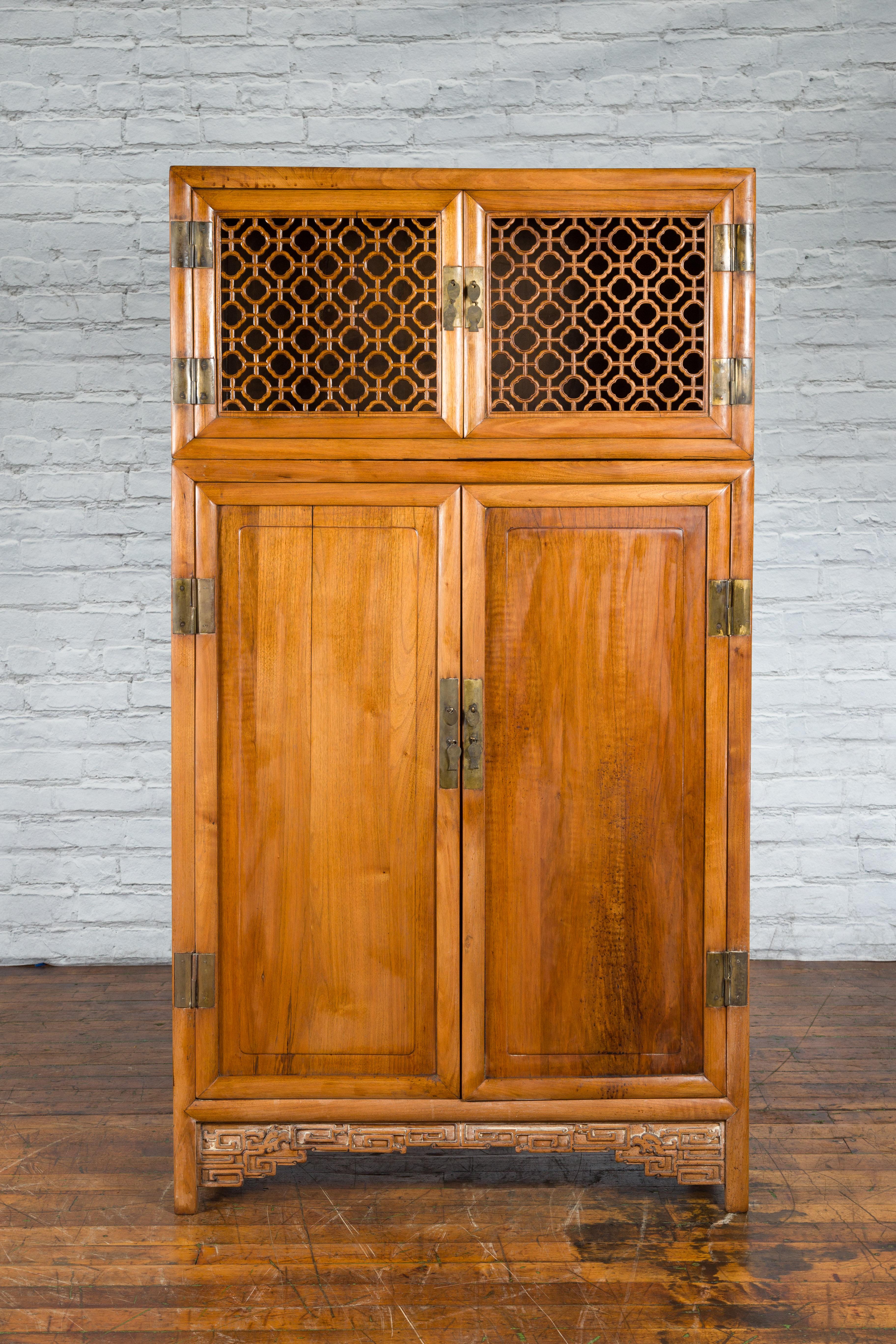 A large Chinese Qing Dynasty period wooden kitchen cabinet from the 19th century with fretwork motifs, carved scrolling apron, brass hardware and hidden drawers. Created in China during the Qing Dynasty period in the 19th century, this large