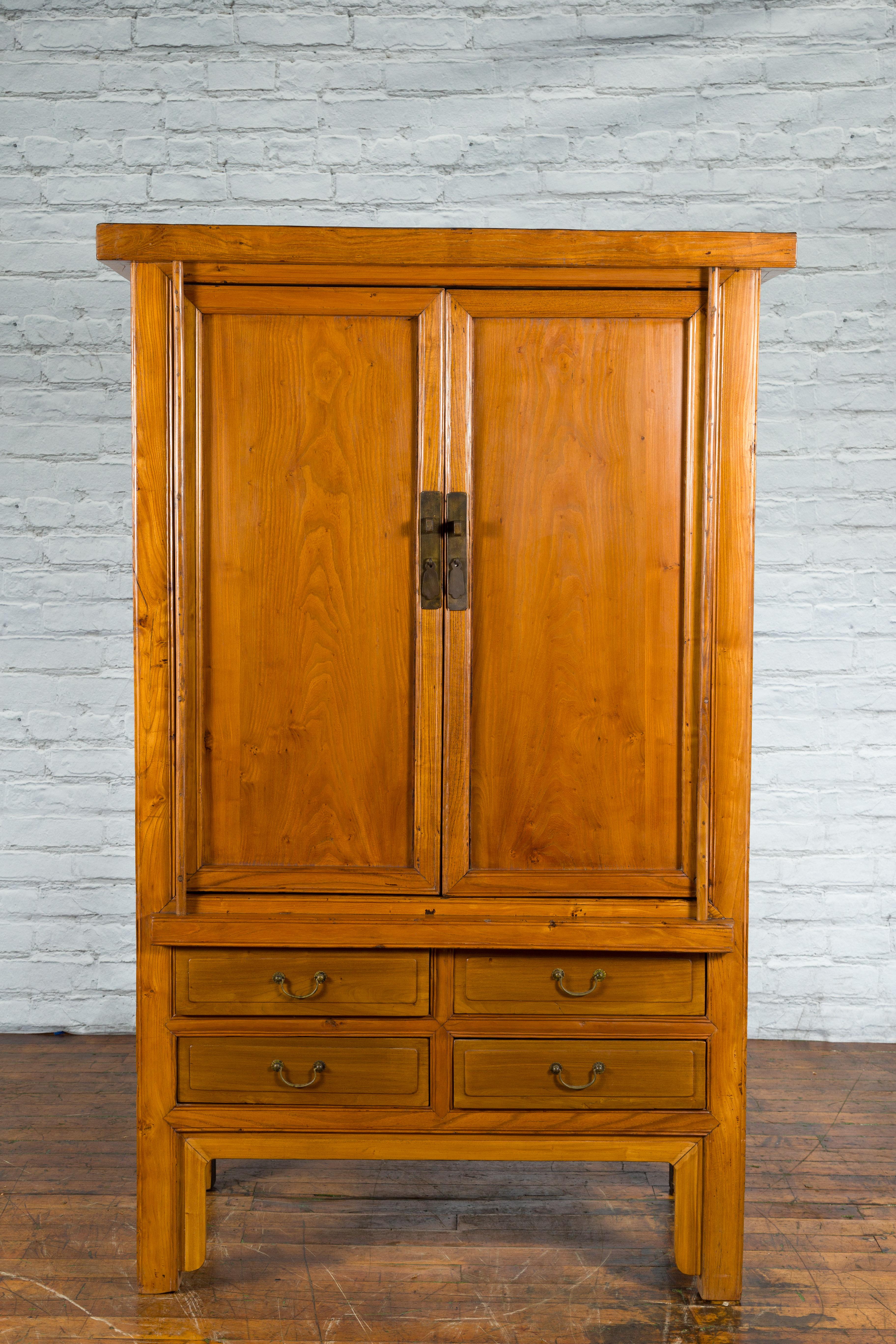 A Chinese Qing Dynasty period wooden cabinet from the 19th century with light lacquer, brass hardware, two doors and four drawers. Created in China during the Qing Dynasty in the 19th century, this wooden cabinet features a linear silhouette