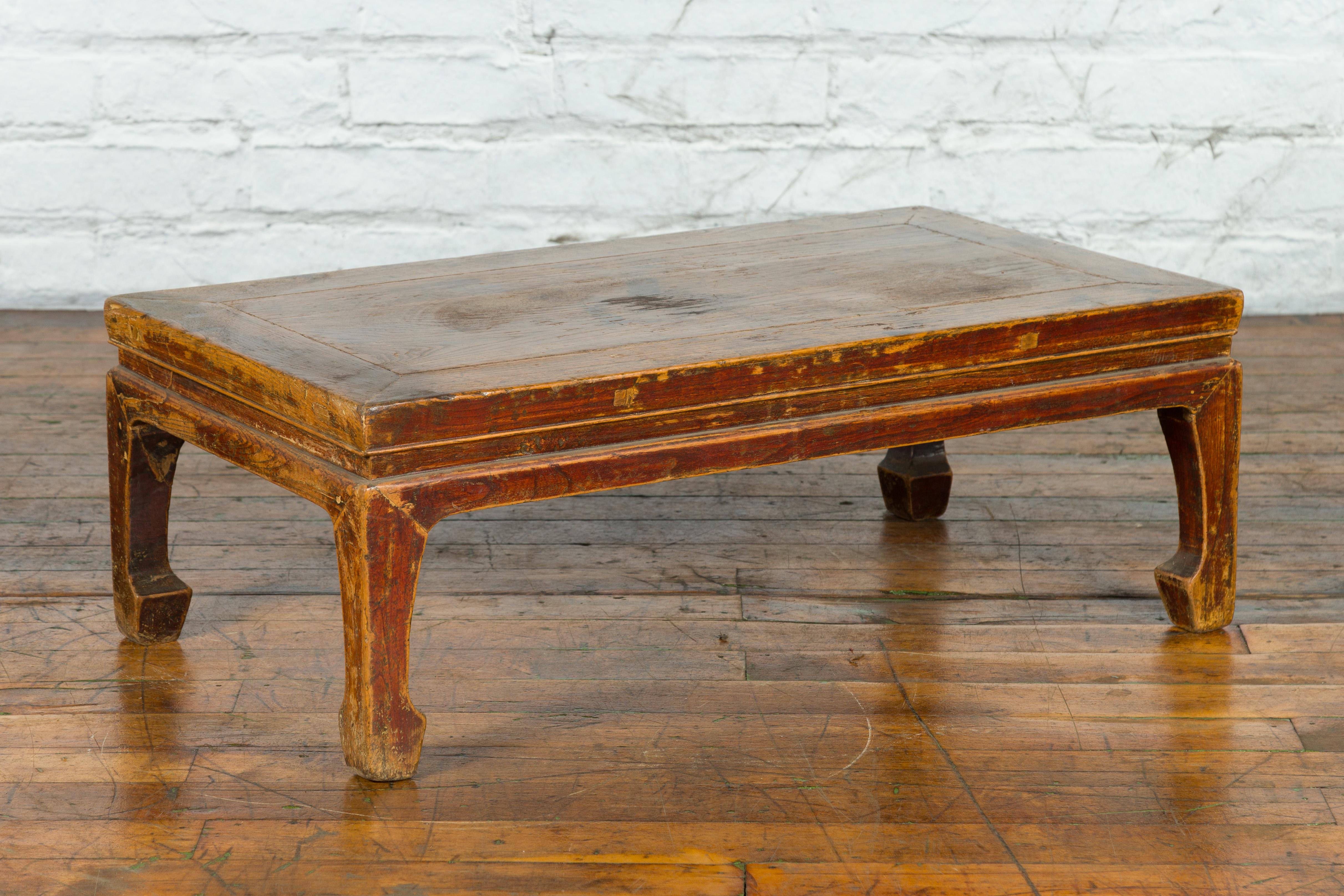 A Chinese Qing Dynasty period low coffee table from the 19th century, with horse hoof legs and distressed patina. Created in China during the Qing Dynasty, this low coffee table features a rectangular waisted top sitting above four short legs with