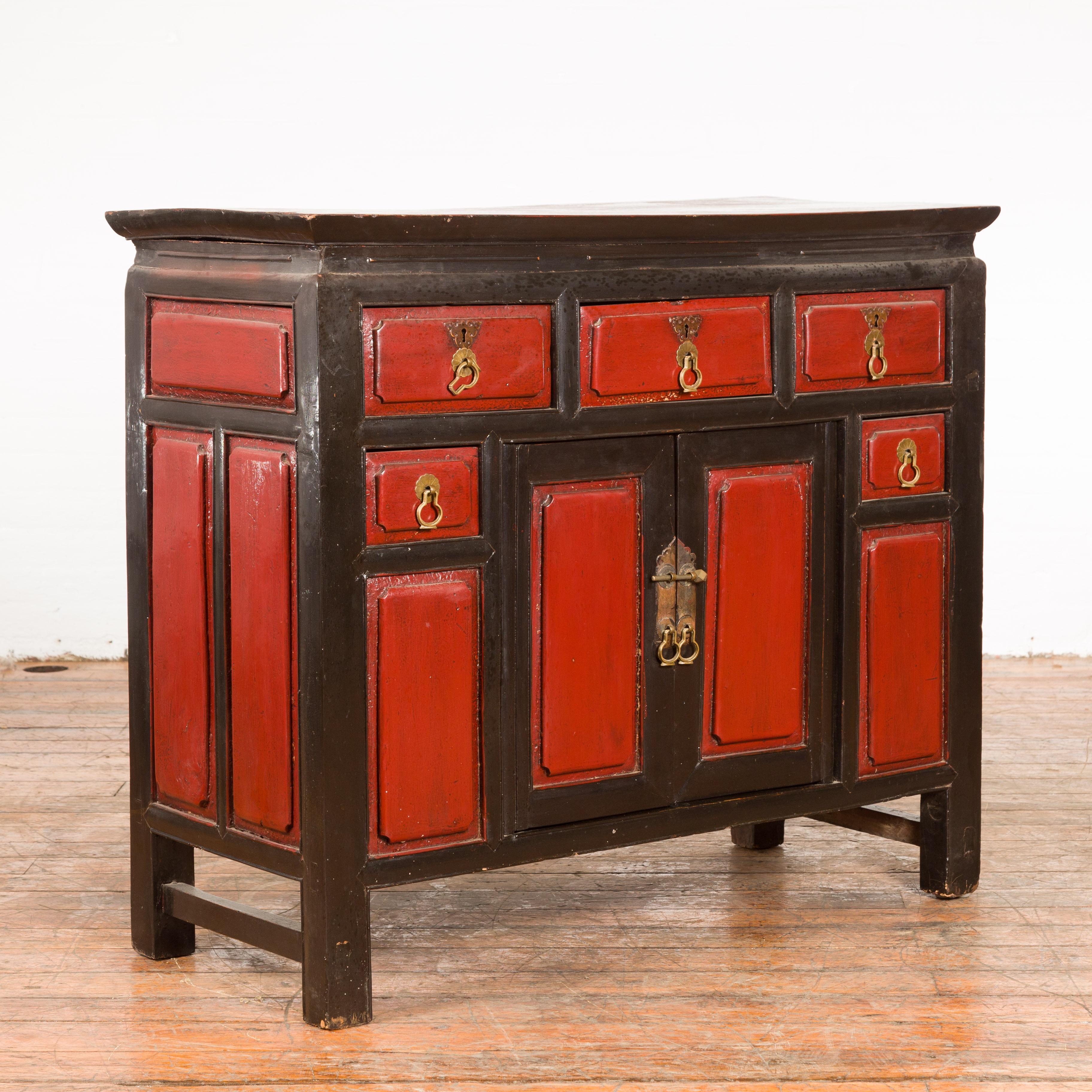A Chinese Qing Dynasty period red and black lacquer cabinet from the 19th century, with five drawers and brass hardware. Created in China during the Qing Dynasty period, this cabinet features a red and black lacquered ground complimenting the