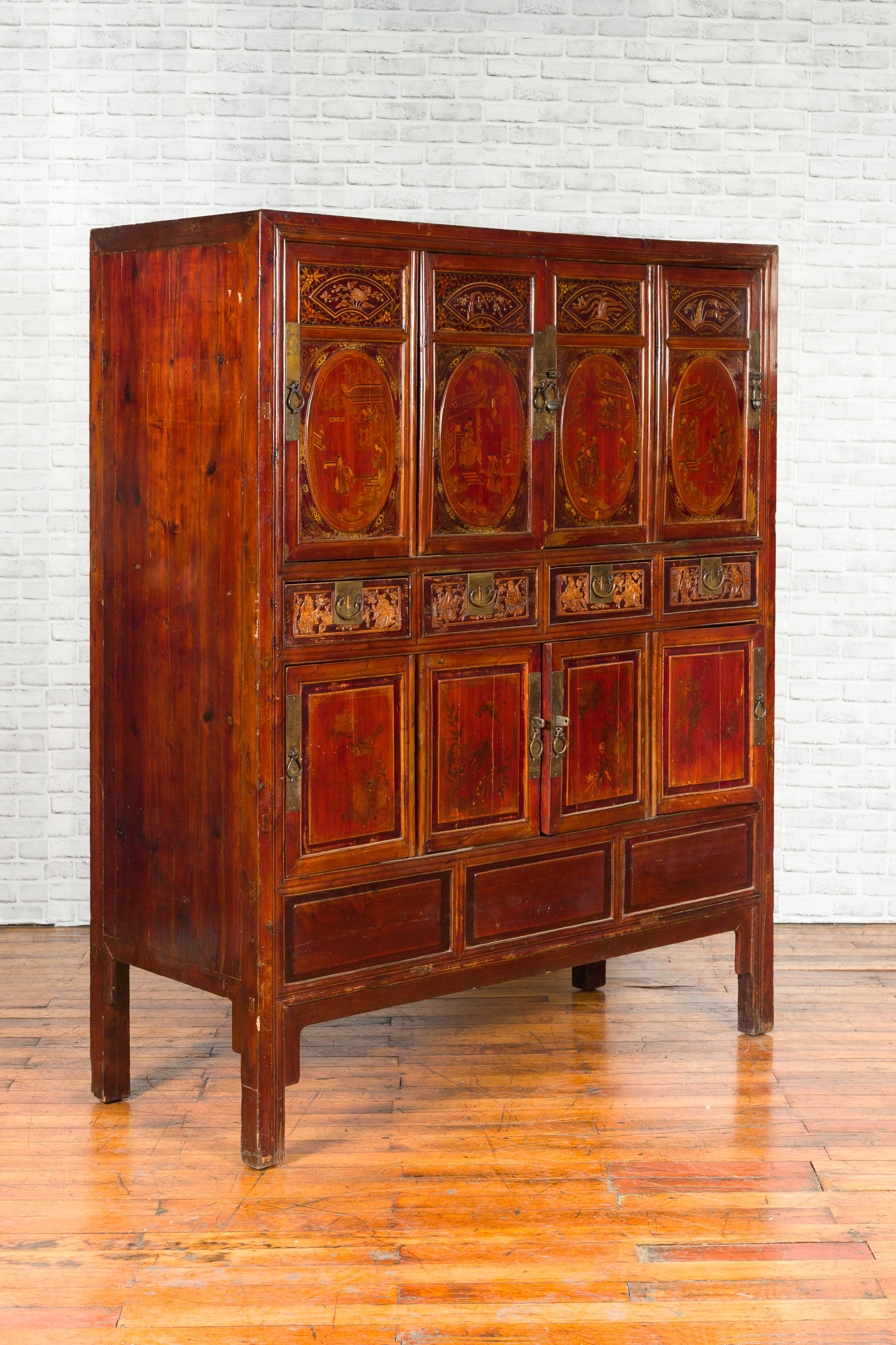 A Chinese Qing Dynasty red cabinet from the 19th century, with oval hand painted medallions and hand carved motifs. Created in China during the 19th century, this Qing cabinet features a linear silhouette perfectly complimented by subtly contrasting