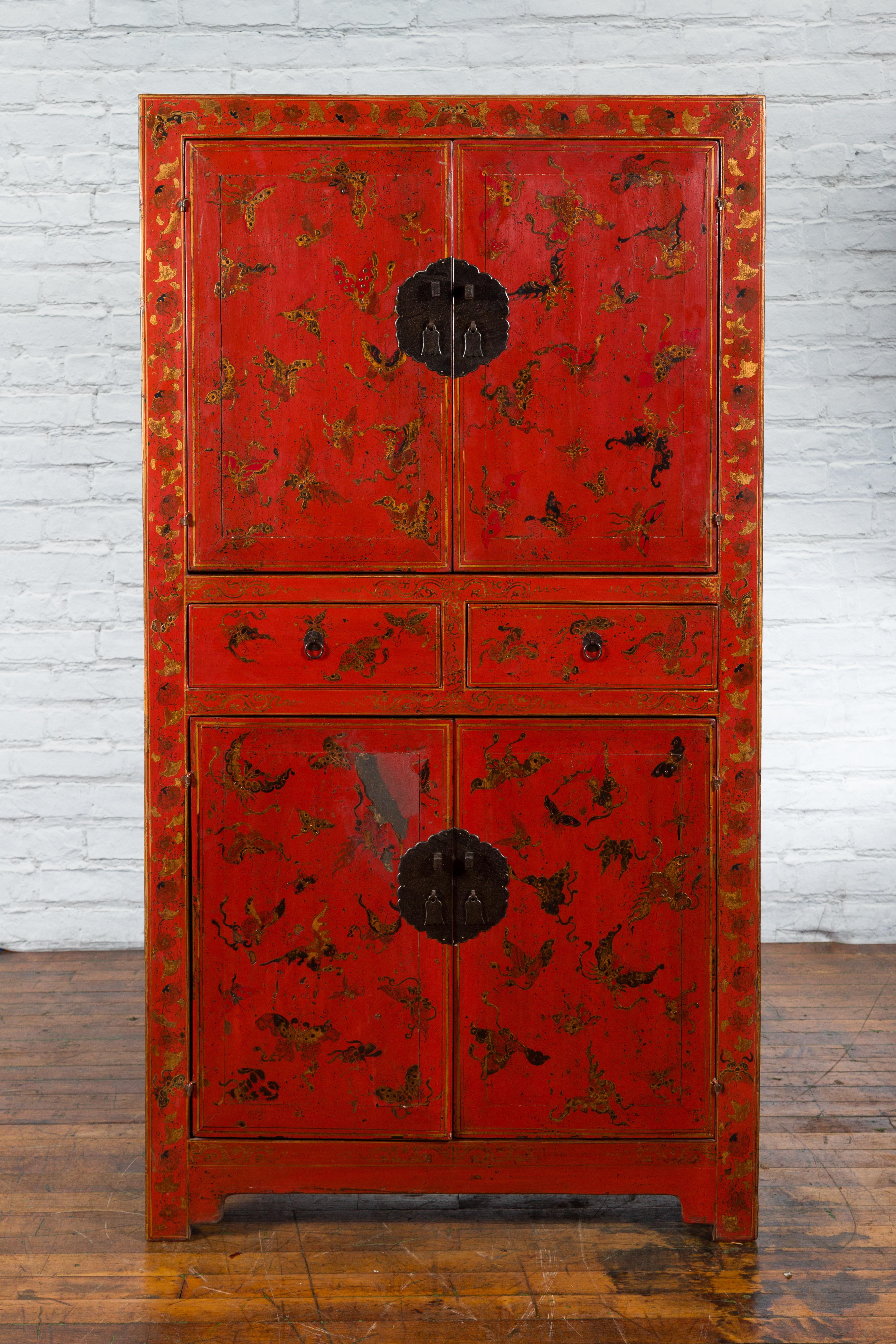 A Chinese Qing Dynasty period red lacquered cabinet from the 19th century with four doors, two drawers and hand-painted butterfly and foliage motifs. Created in China during the Qing Dynasty period in the 19th century, this tall cabinet features a