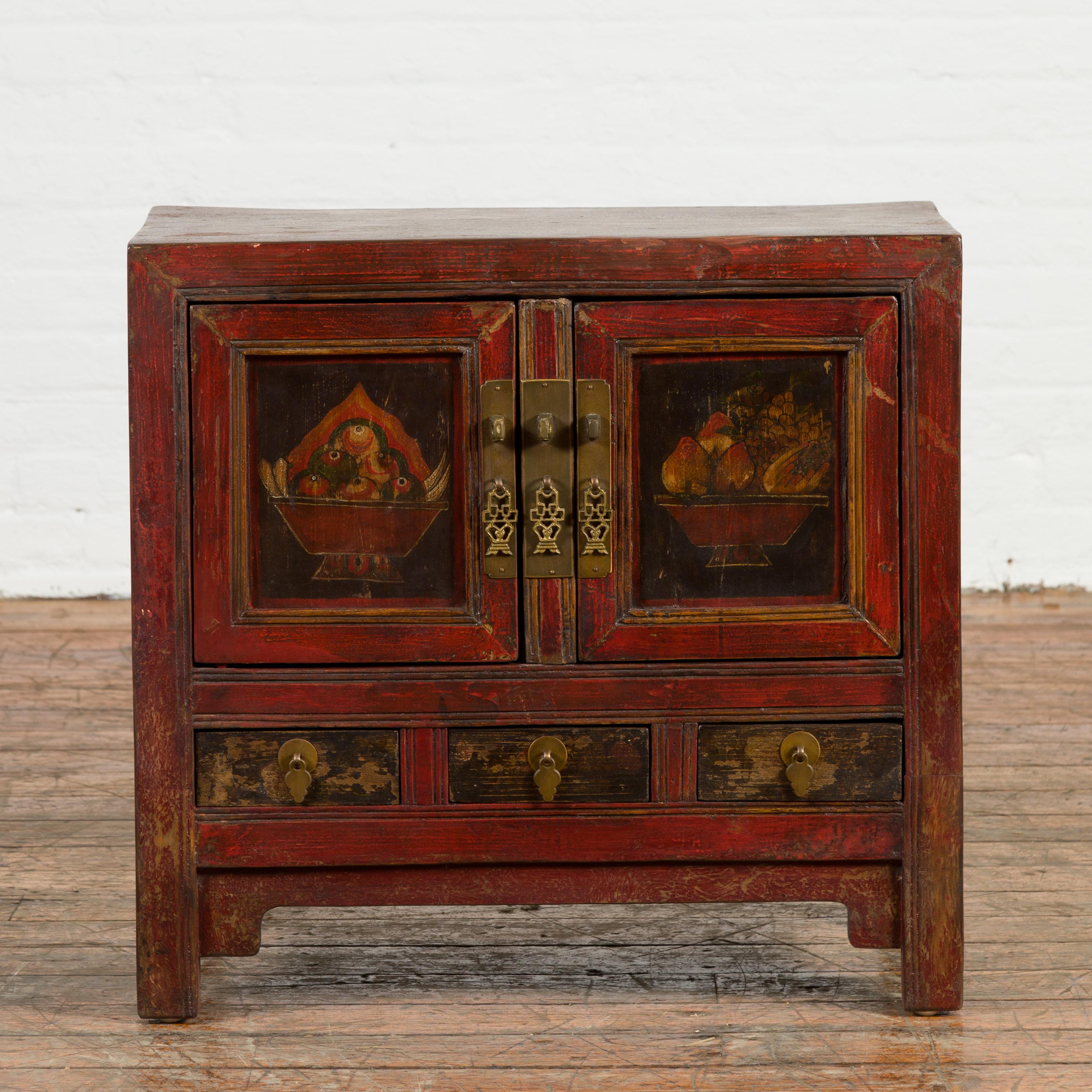 A Chinese Qing Dynasty period small red lacquer cabinet from the 19th century, with painted fruit baskets and brass hardware. Created in China during the Qing Dynasty, this small cabinet features a rectangular top sitting above two doors and three