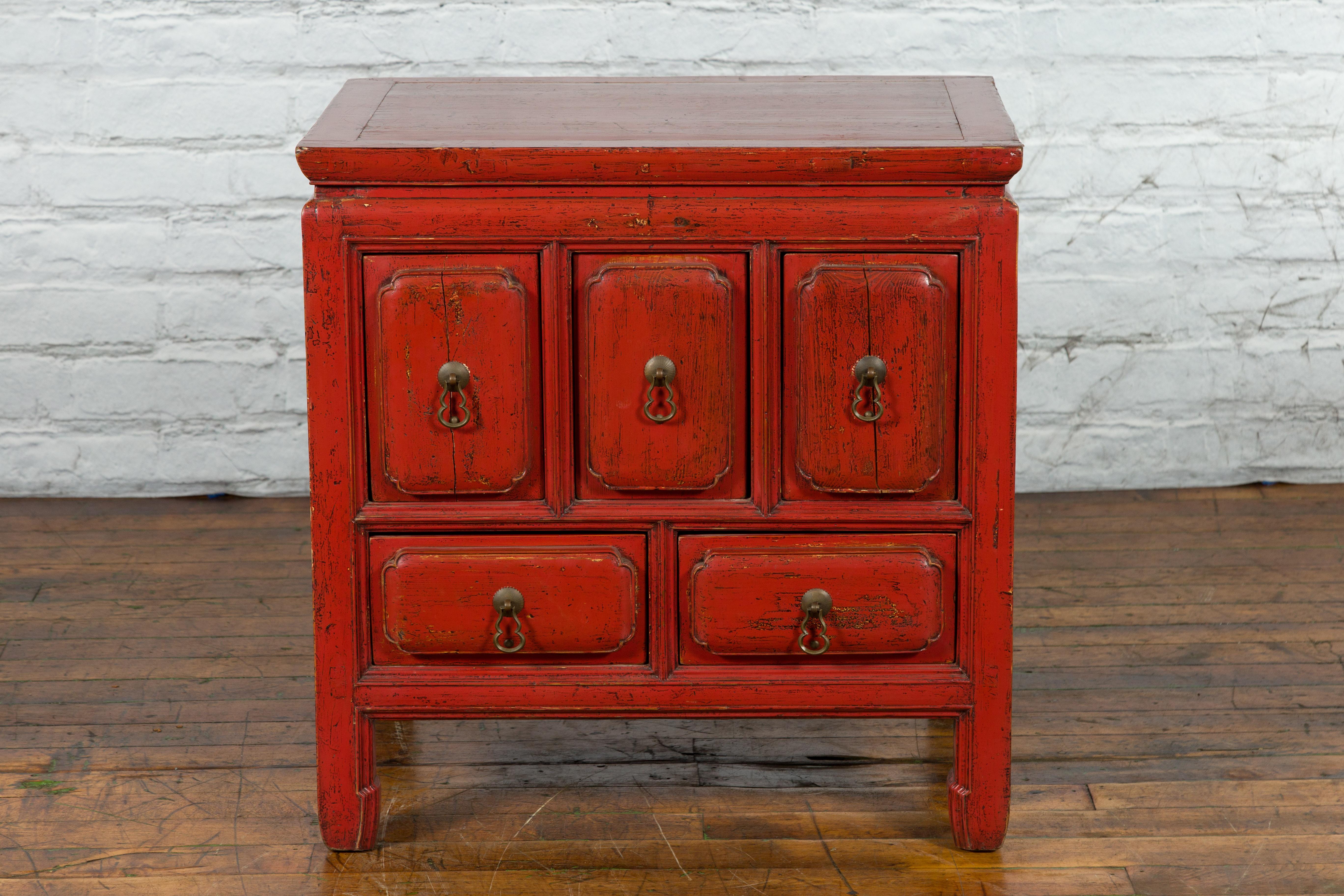 A Chinese Qing Dynasty period red lacquer side chest from the 19th century with five hand-carved raised drawers, hints of a black lacquer and horse hoof legs. Created in China during the Qing Dynasty, this side cabinet features a linear silhouette