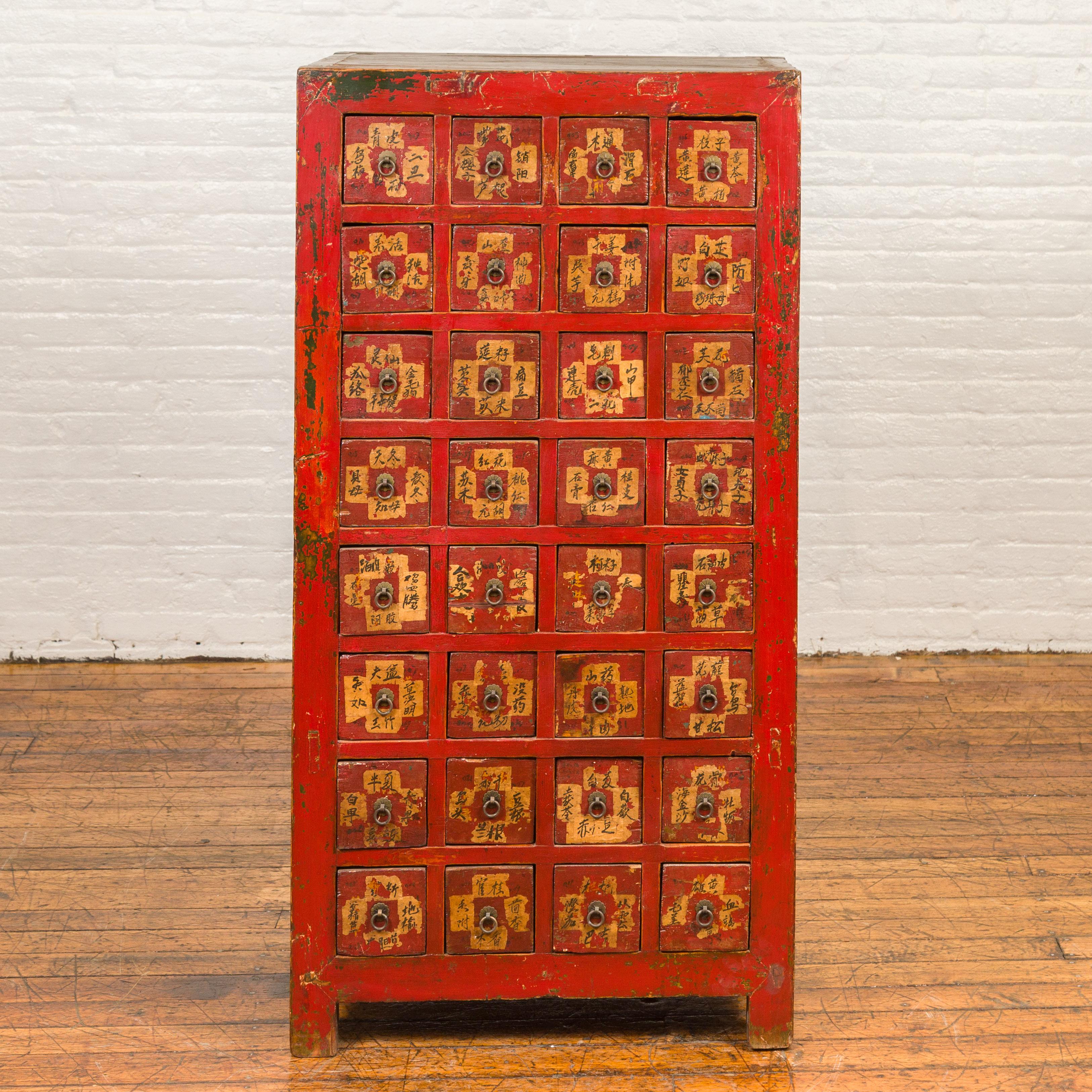 A Chinese Qing dynasty red lacquered apothecary chest from the 19th century, with 32 drawers and calligraphed painted labels. Crafted in China during the Qing dynasty period, this tall apothecary chest boasting a red lacquered body and a nicely