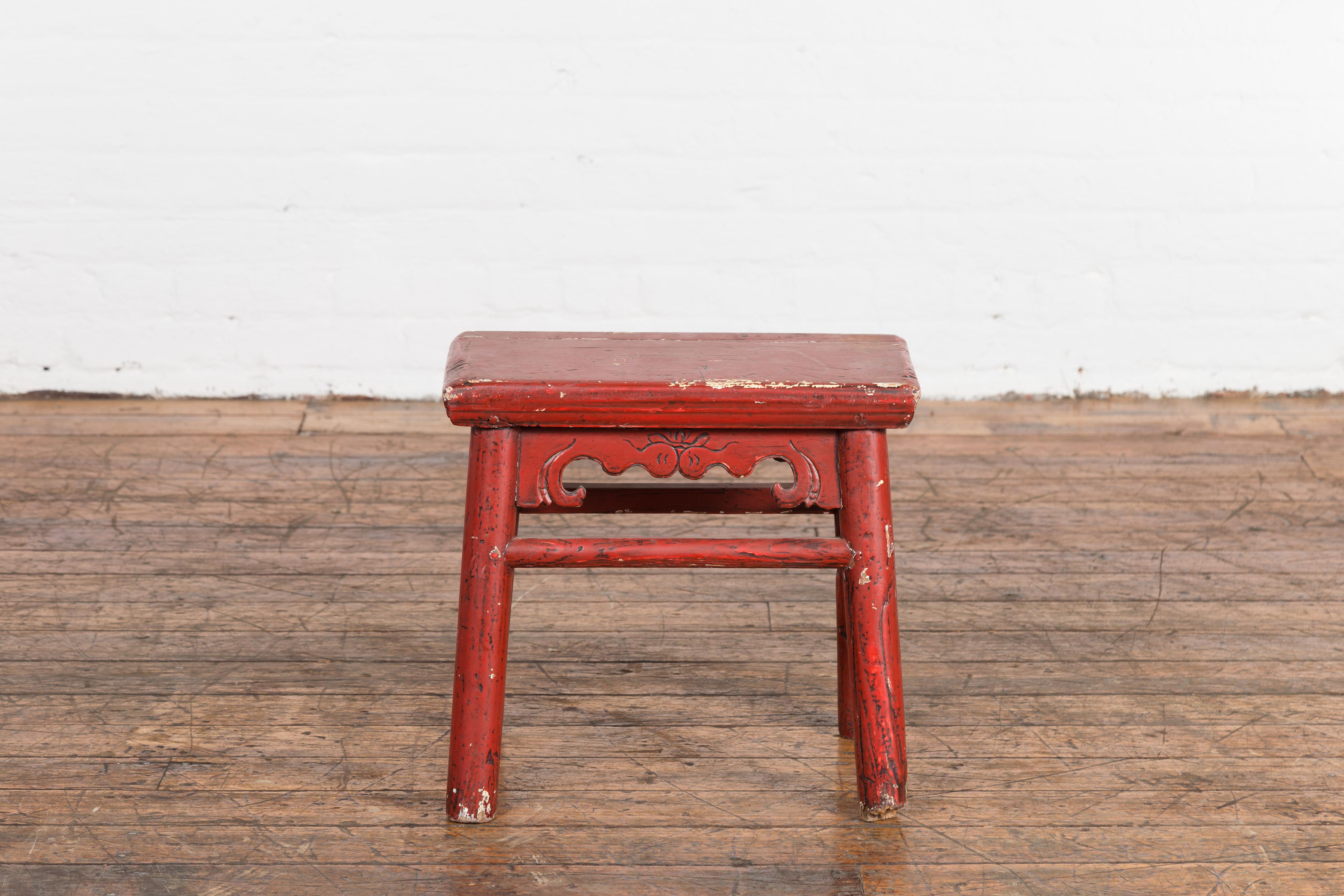 A Chinese Qing Dynasty period A Frame red lacquered wooden stool from the 19th century, with carved apron, side stretchers and weathered patina. Created in China during the Qing Dynasty period in the 19th century, this wooden A Frame stool showcases
