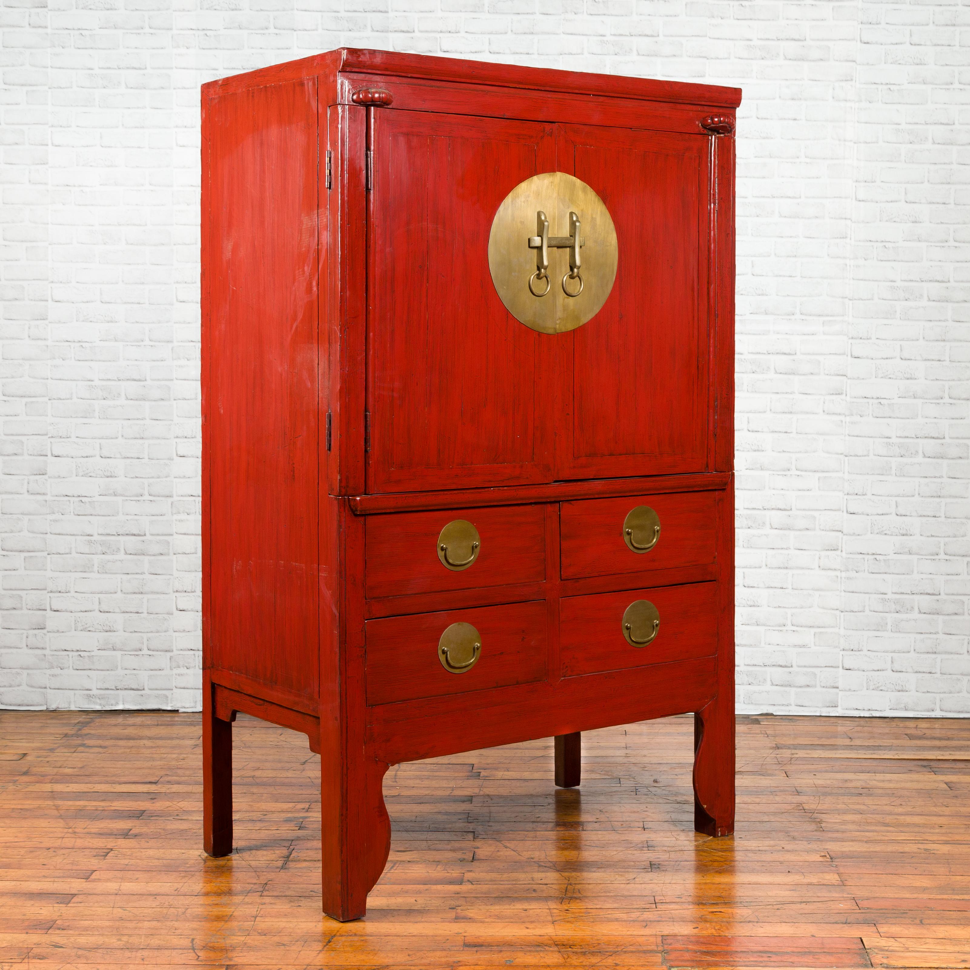 A Northern Chinese Qing Dynasty period red lacquered wedding cabinet from the 19th century, with large brass medallion, two doors and four drawers. Created in Ming Bo (North China) during the Qing Dynasty period, this red cabinet features two upper