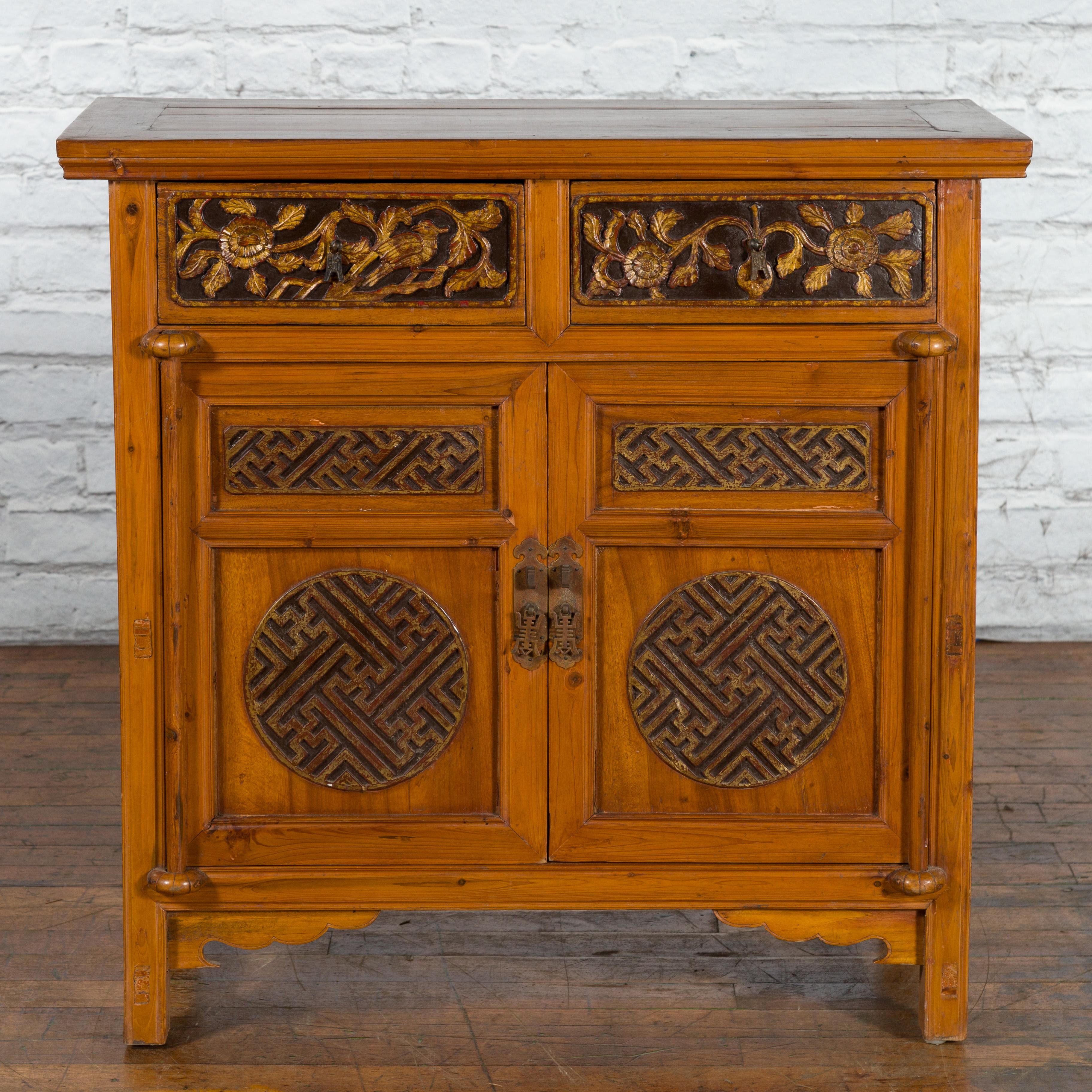 A Chinese Qing Dynasty period side cabinet from the 19th century with carved drawers, gilt accents, fretwork motifs and brass hardware. Created in China during the Qing Dynasty period in the 19th century, this side cabinet features a rectangular top
