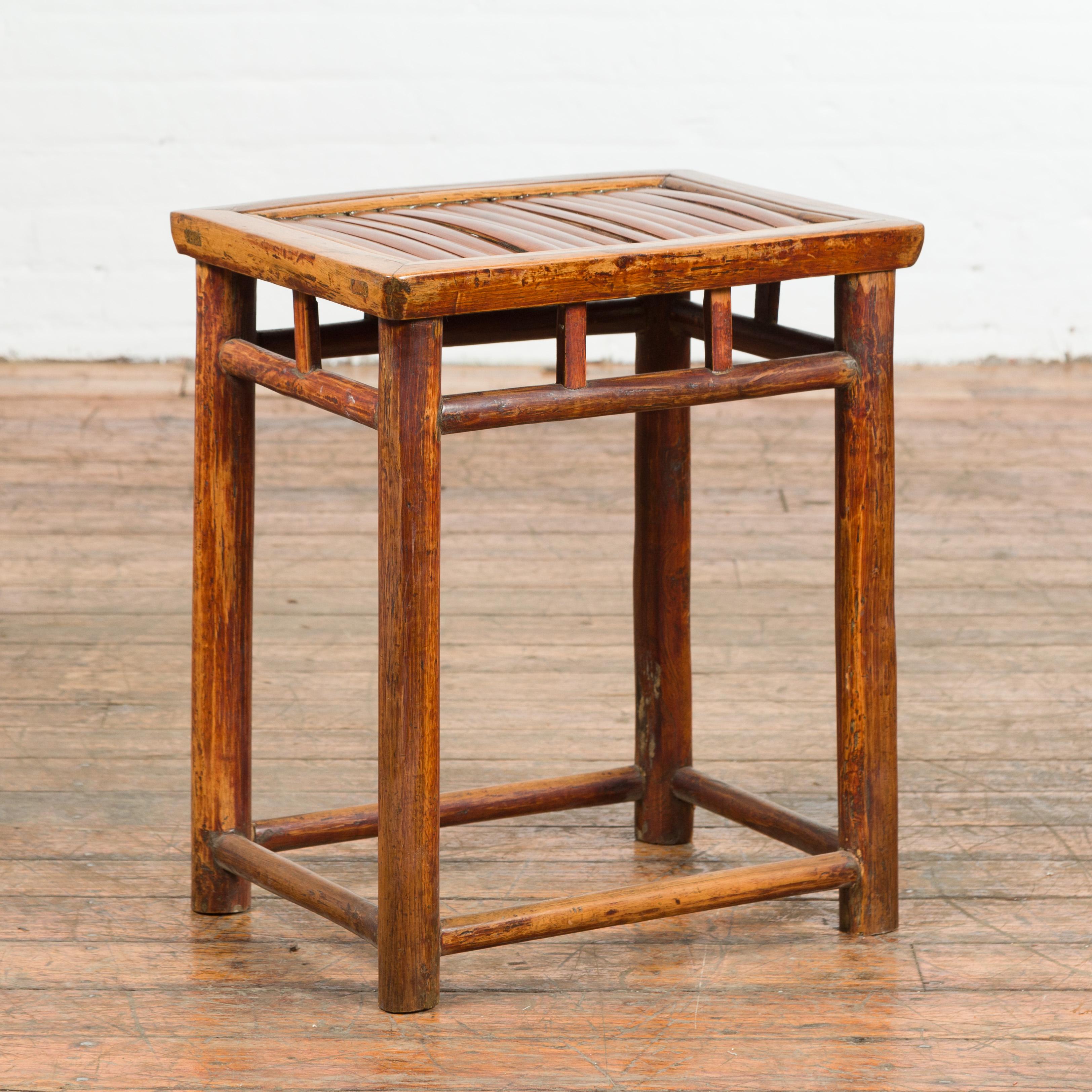 A Chinese antique Qing Dynasty side table from the 19th century, with split bamboo top and pillar strut motifs. Created in China during the Qing Dynasty, this unusual side table features a rectangular top made of split bamboo, resting above an open