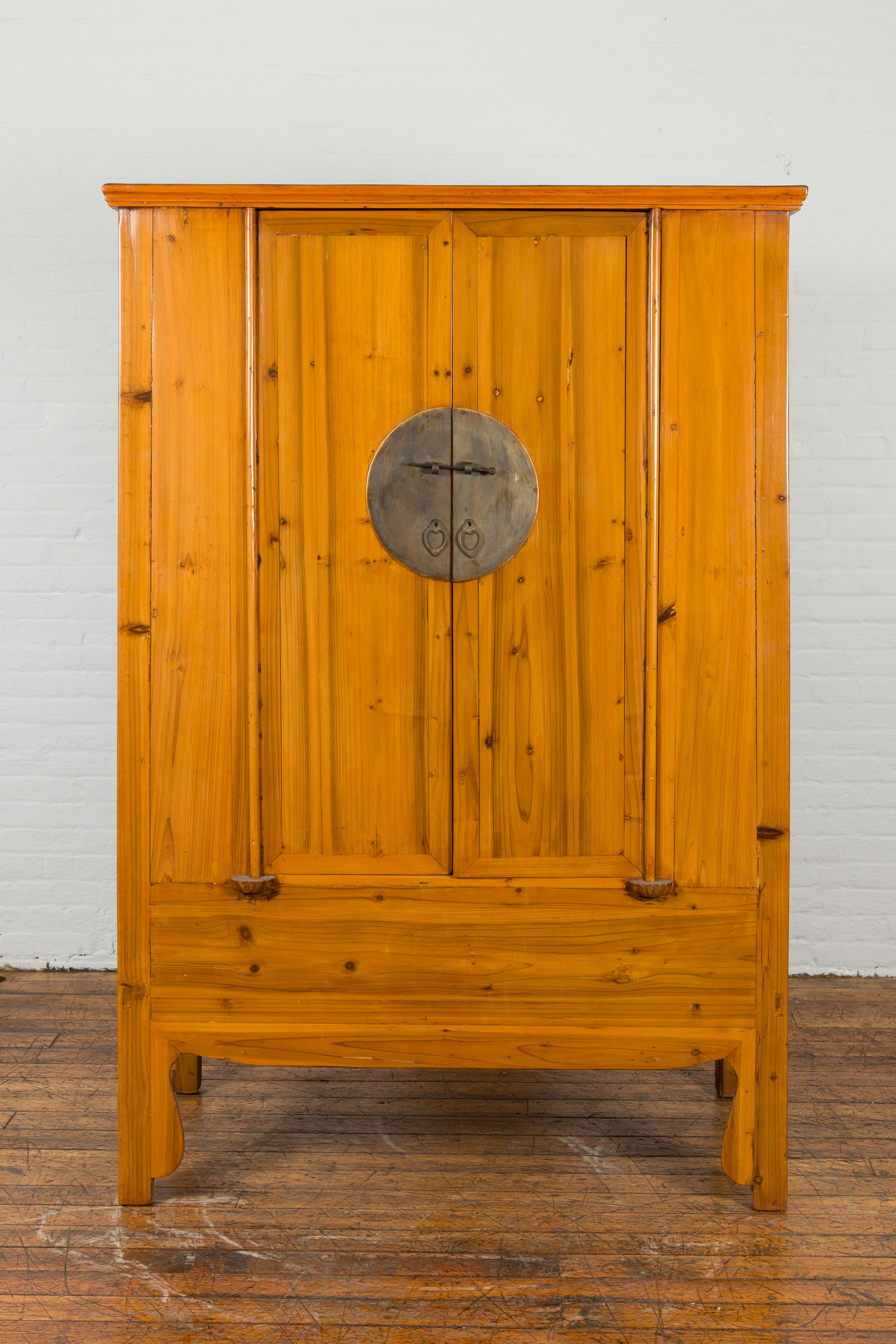 A Chinese Qing Dynasty period tapered cabinet from the 19th century, with round medallion hardware. Created in China during the Qing Dynasty, this wooden cabinet features a tapered silhouette made of two narrow doors accented with a large brass