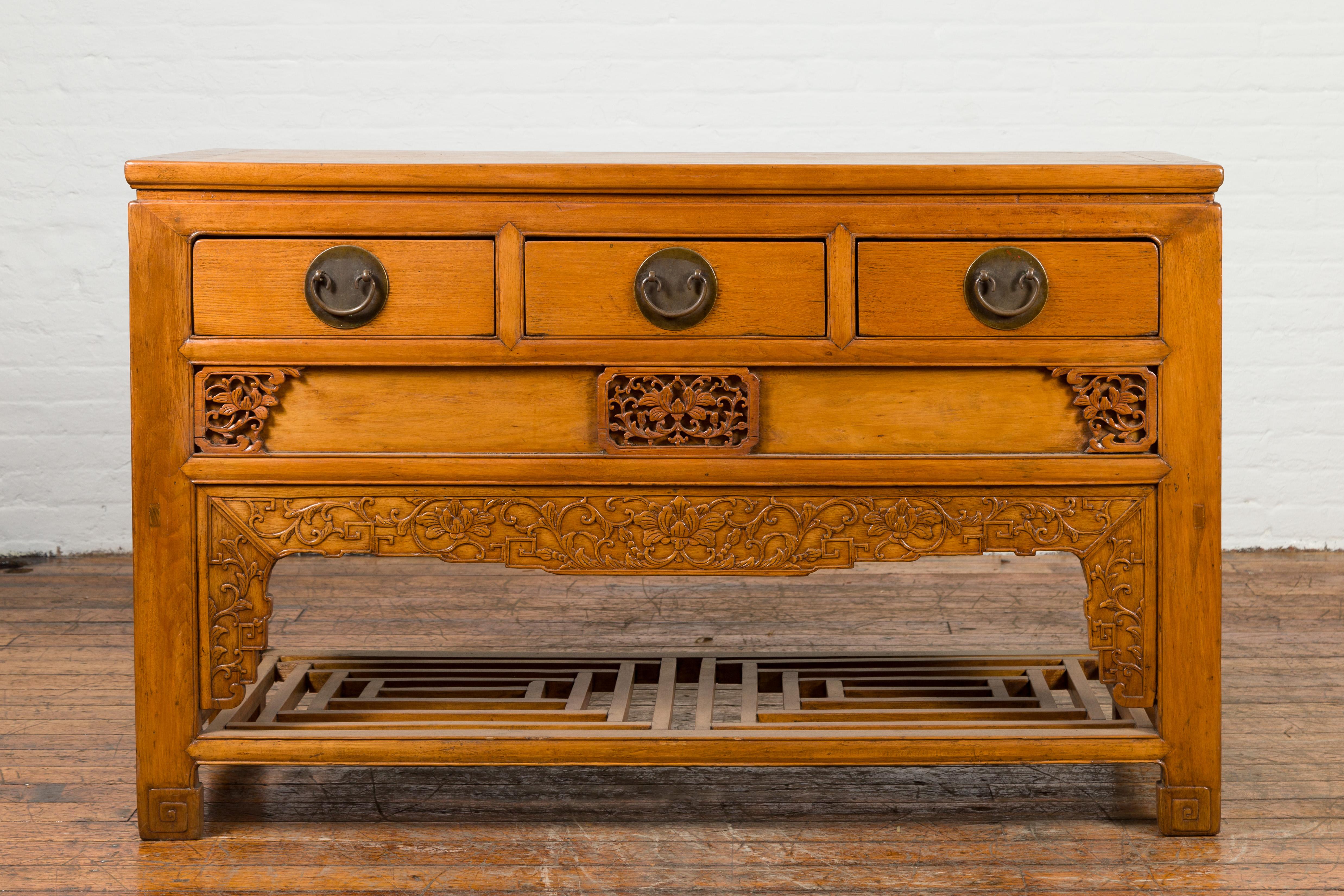 A Chinese Qing Dynasty period carved wooden waisted sideboard from the 19th century, with three drawers and lower shelf. Created in China during the Qing Dynasty, this waisted sideboard features a rectangular top with central board, sitting above