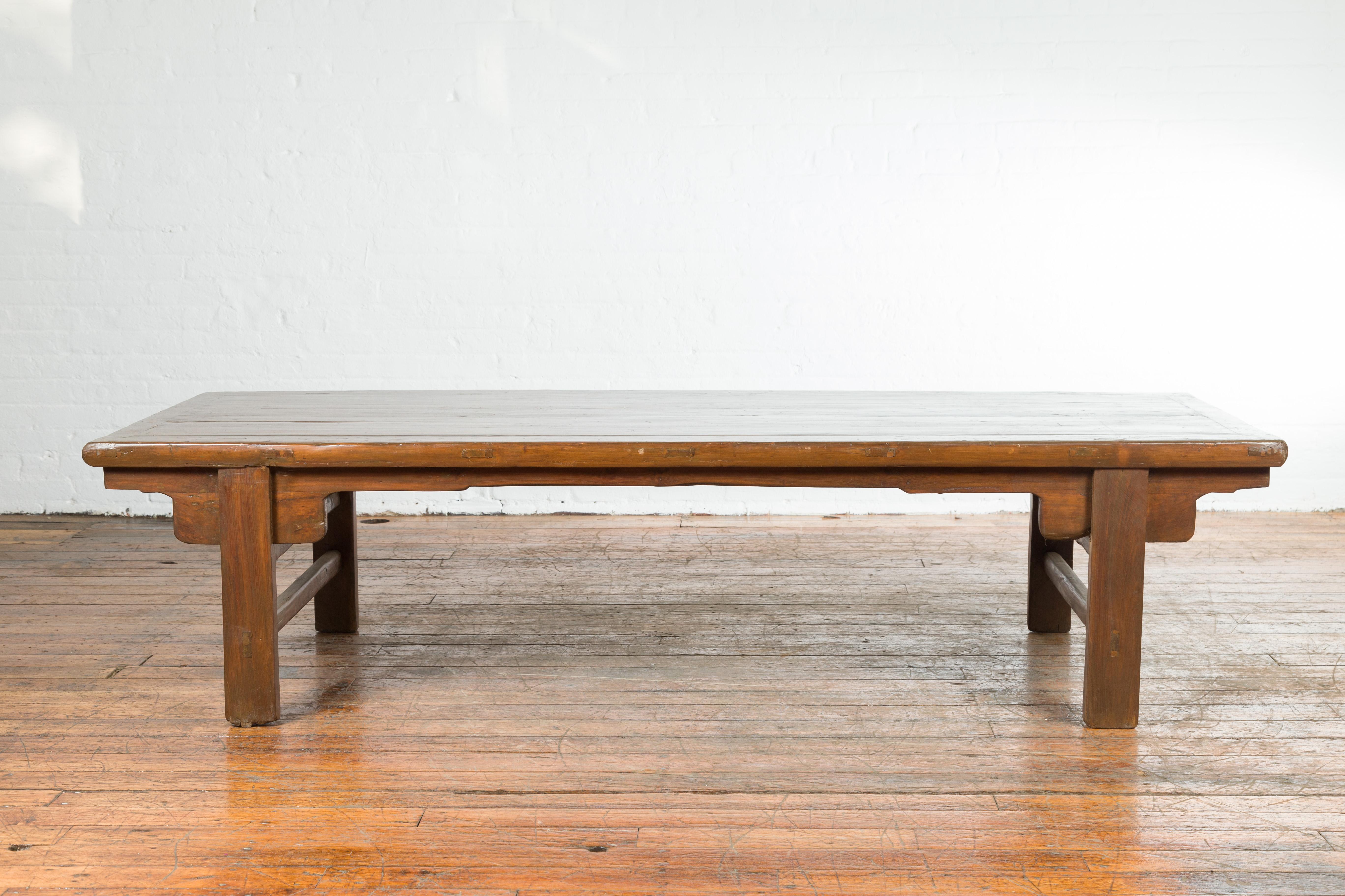 A Chinese Qing Dynasty period wide coffee table from the 19th century, with carved spandrels and side stretchers. Created in China during the Qing Dynasty period, this coffee table features a wide rectangular planked top sitting above four straight