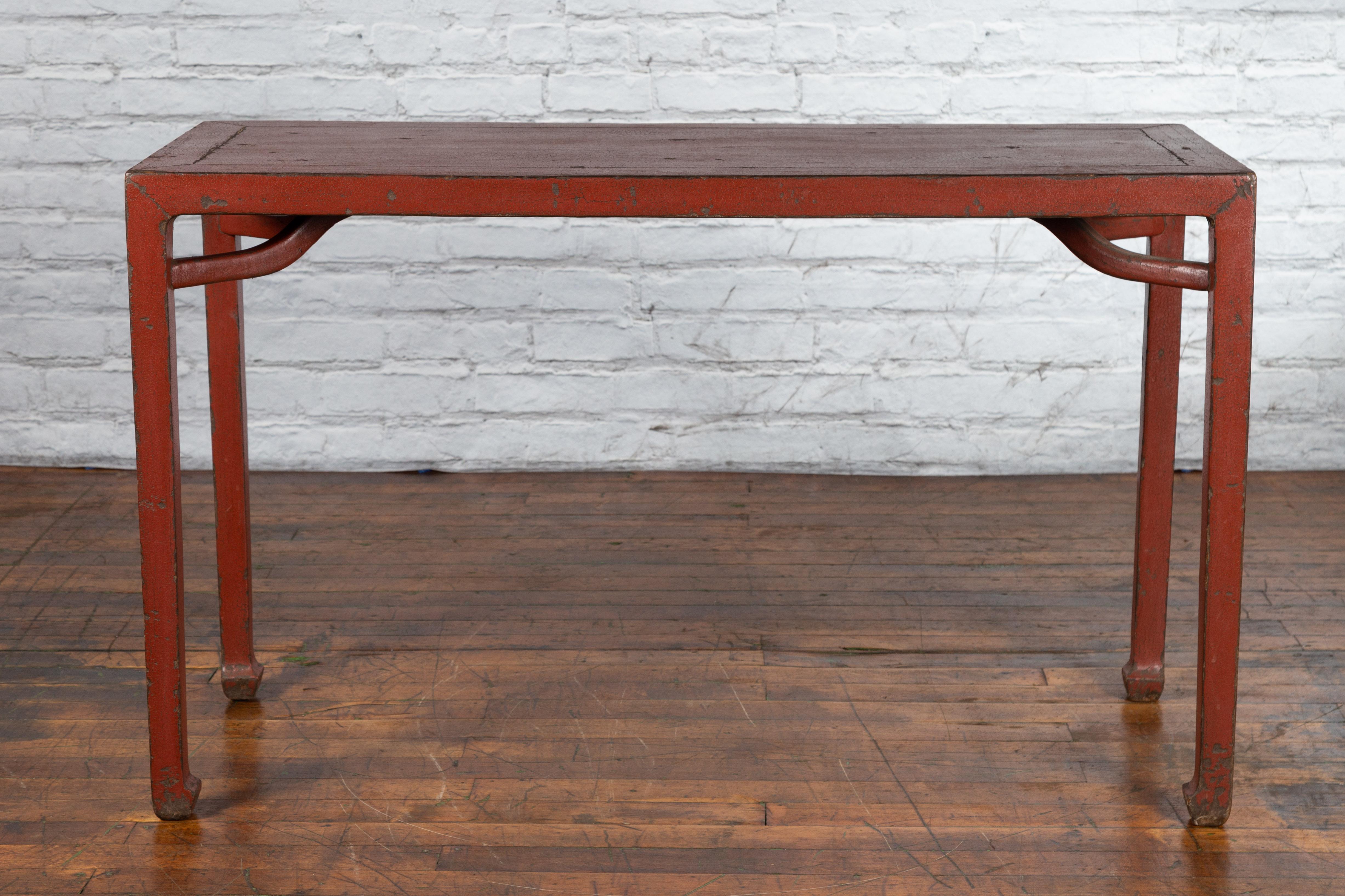 An antique Chinese Qing Dynasty period red lacquered console table from the 19th century with original patina. Created in China during the Qing Dynasty, this console table features a rectangular top with central board, sitting above four straight