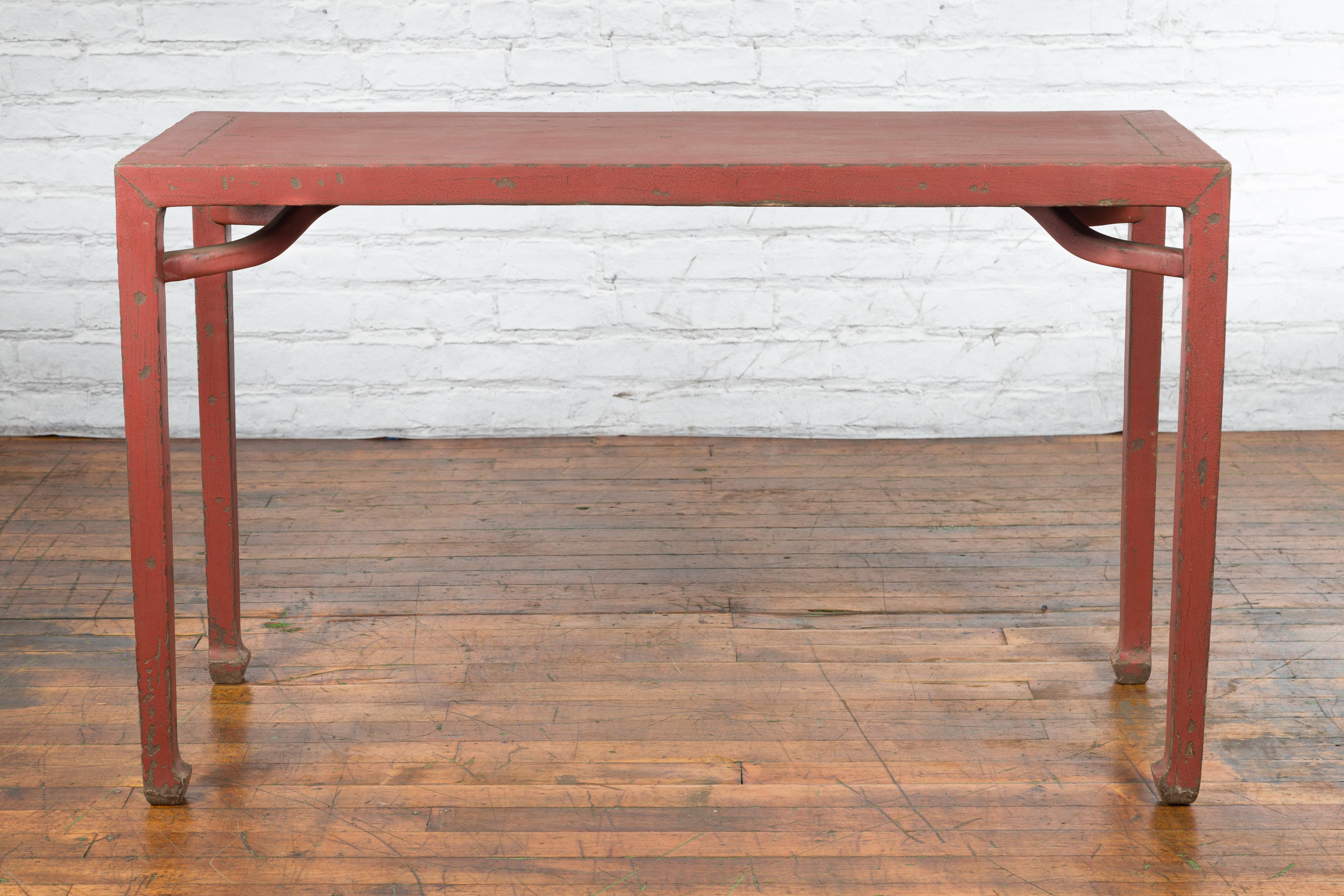 A Chinese Qing Dynasty period yumu wood wine console table from the 19th century, with original red lacquer and horse hoof extremities. Created in China during the Qing Dynasty, this yumu wood table features a rectangular top with central board,