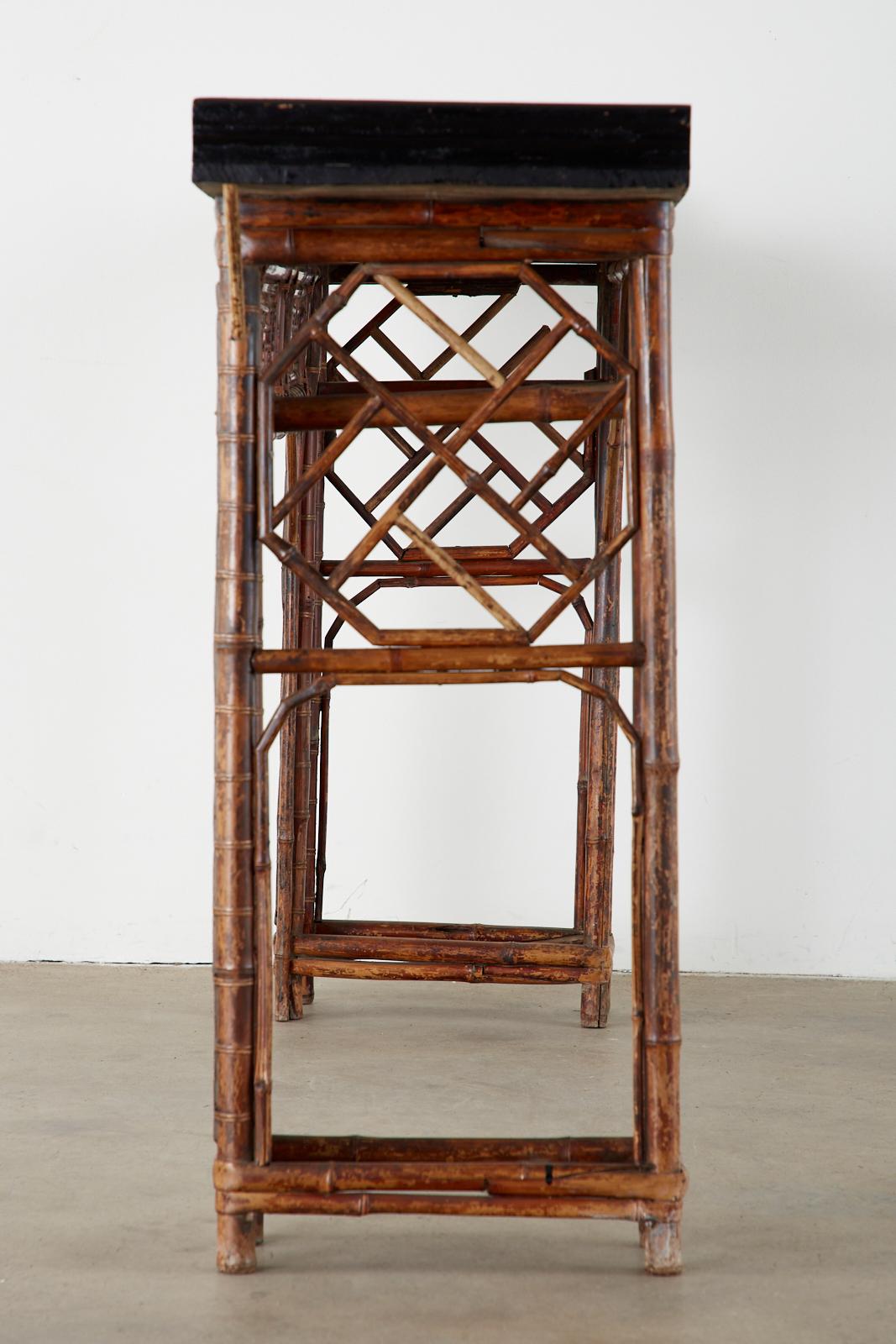Late 19th century Chinese Qing Dynasty altar table or console. Constructed from tortoiseshell finish bamboo having a double pedestal topped with a lacquered elm top. The frame is intricately decorated with an open fretwork lattice design. The frieze