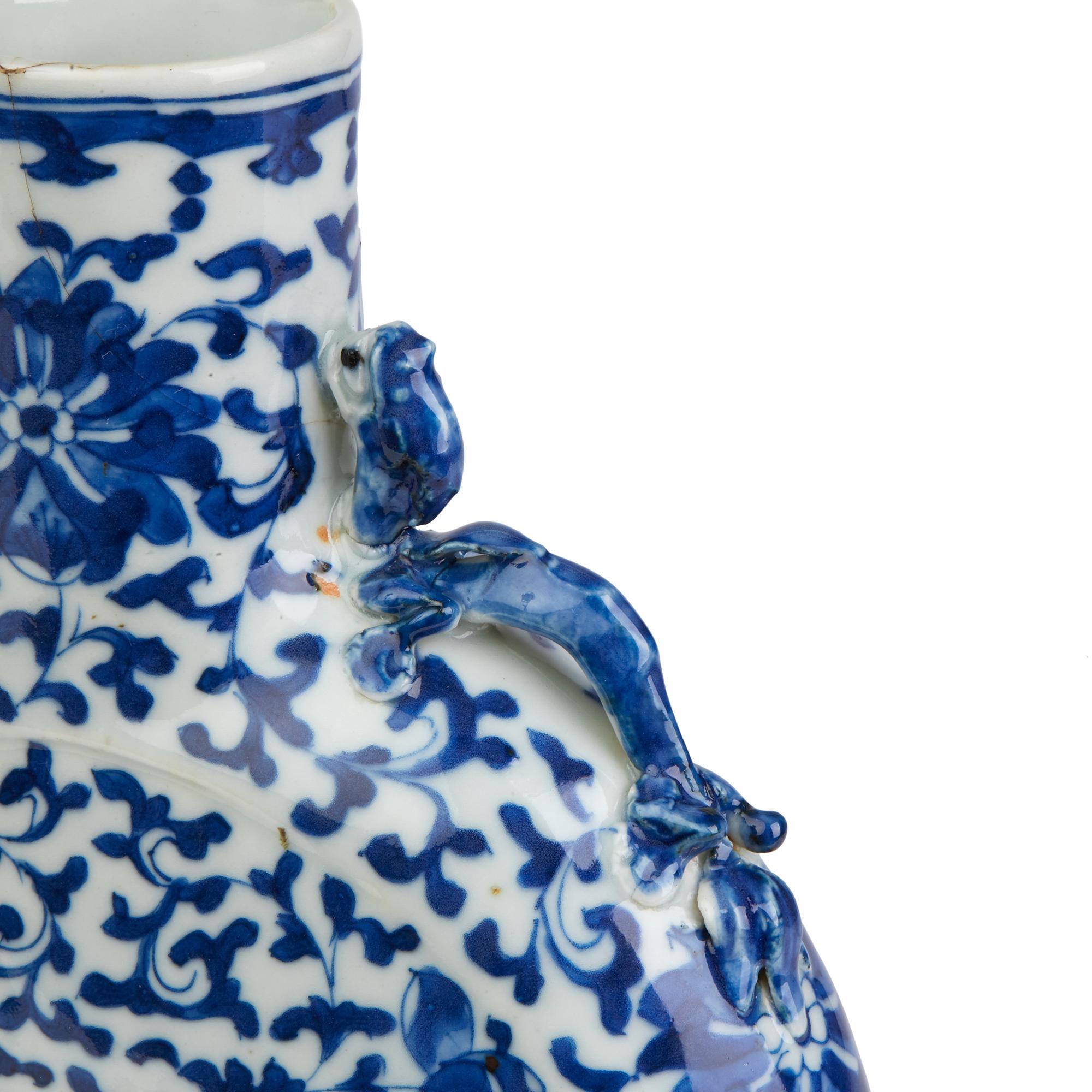 A fine antique Chinese porcelain moon shaped vase with kylin to the shoulders and decorated with trailing blossoms in blue on a white ground. The vase stands on a oval shaped foot with an unglazed rim with a flat moon shaped body and short straight