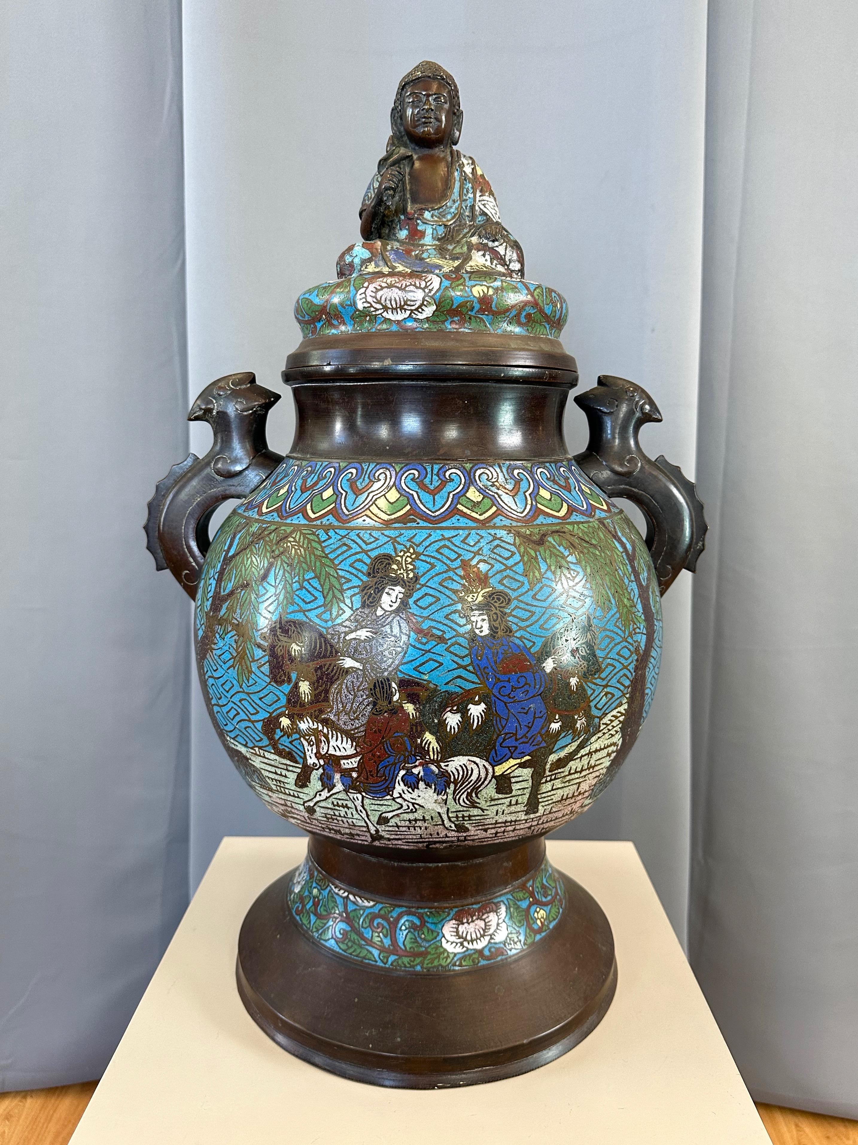 A circa 1915 antique Japanese Taishō period larger-size bronze champlevé urn or vessel with buddha figure lid and familial scene on body.

Cast bronze form with very handsome and uniform dark brown natural patina and colorful champlevé—rather than