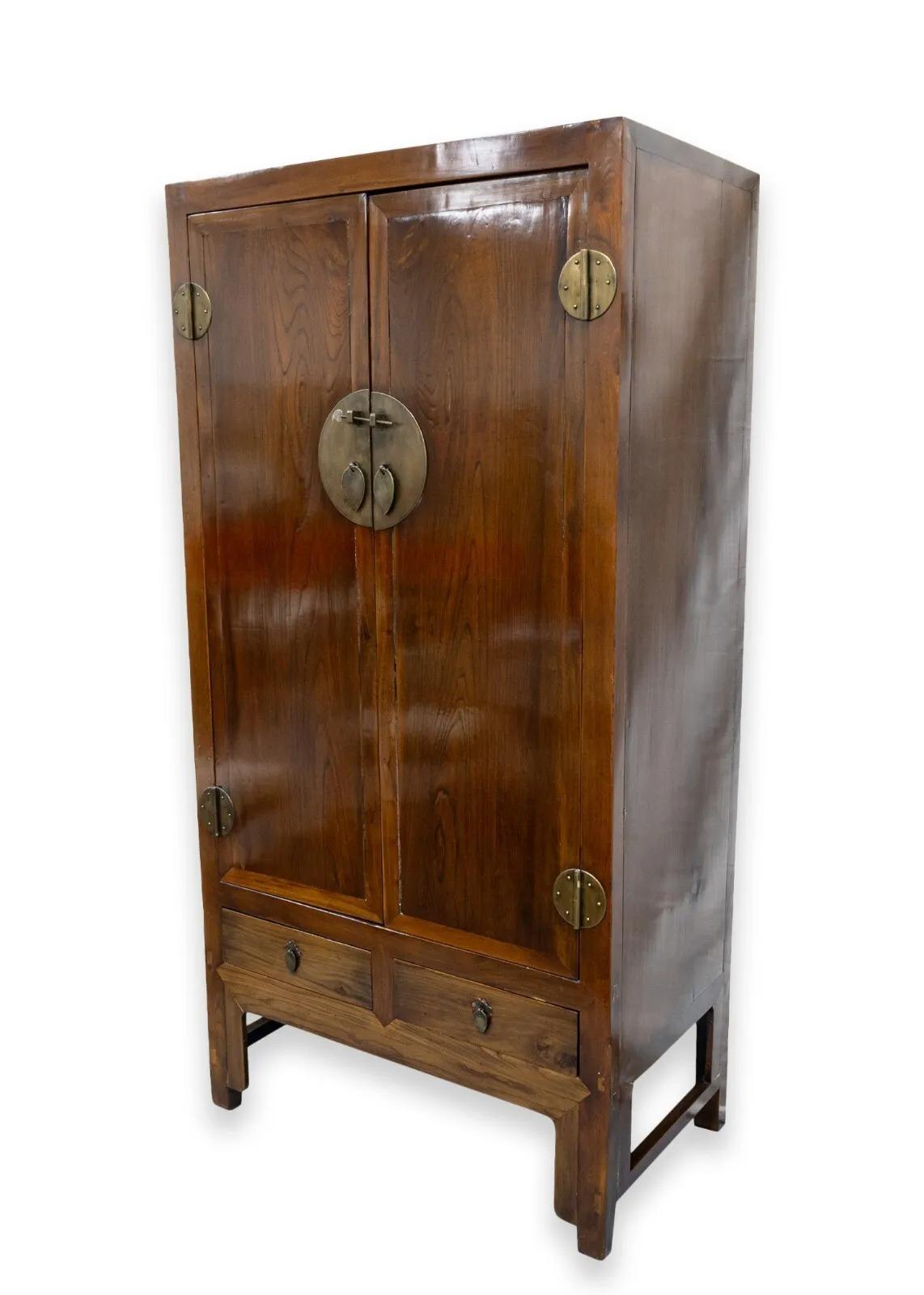 A vintage Qing Dynasty style Asian armoire cabinet. A stunning piece of furniture to add to your living room or bedroom space. This lovely cabinet features a full wood construction with a dark, rich coloration and beautiful grain. The face features