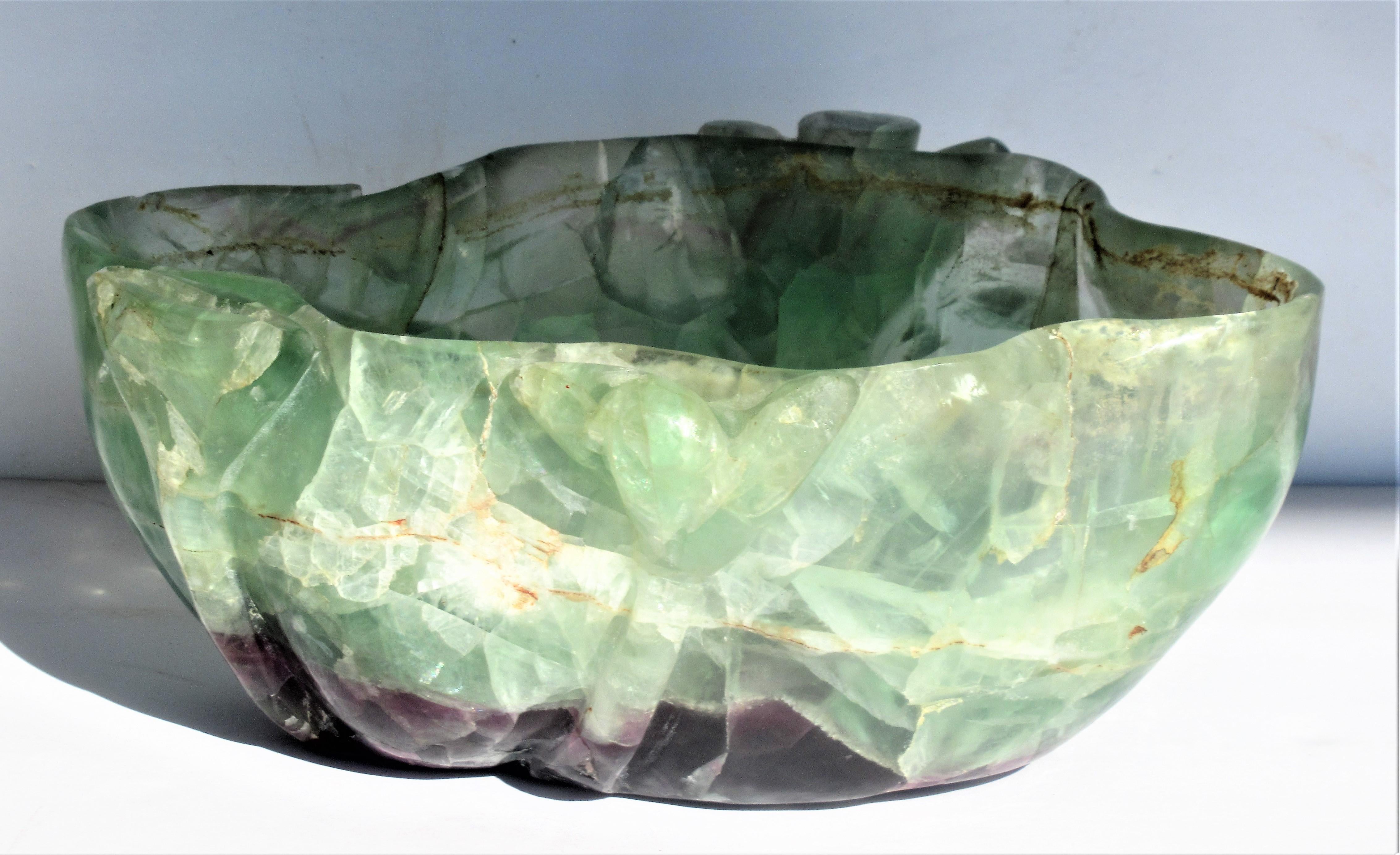 Carved fluorite bowl with wood stand. The four lobed bowl with natural fissures, beautiful deep amethyst color at interior and exterior bottom and three carved long stemmed flowers going up outside of bowl. Chinese - Qing Dynasty - Circa 1880 -