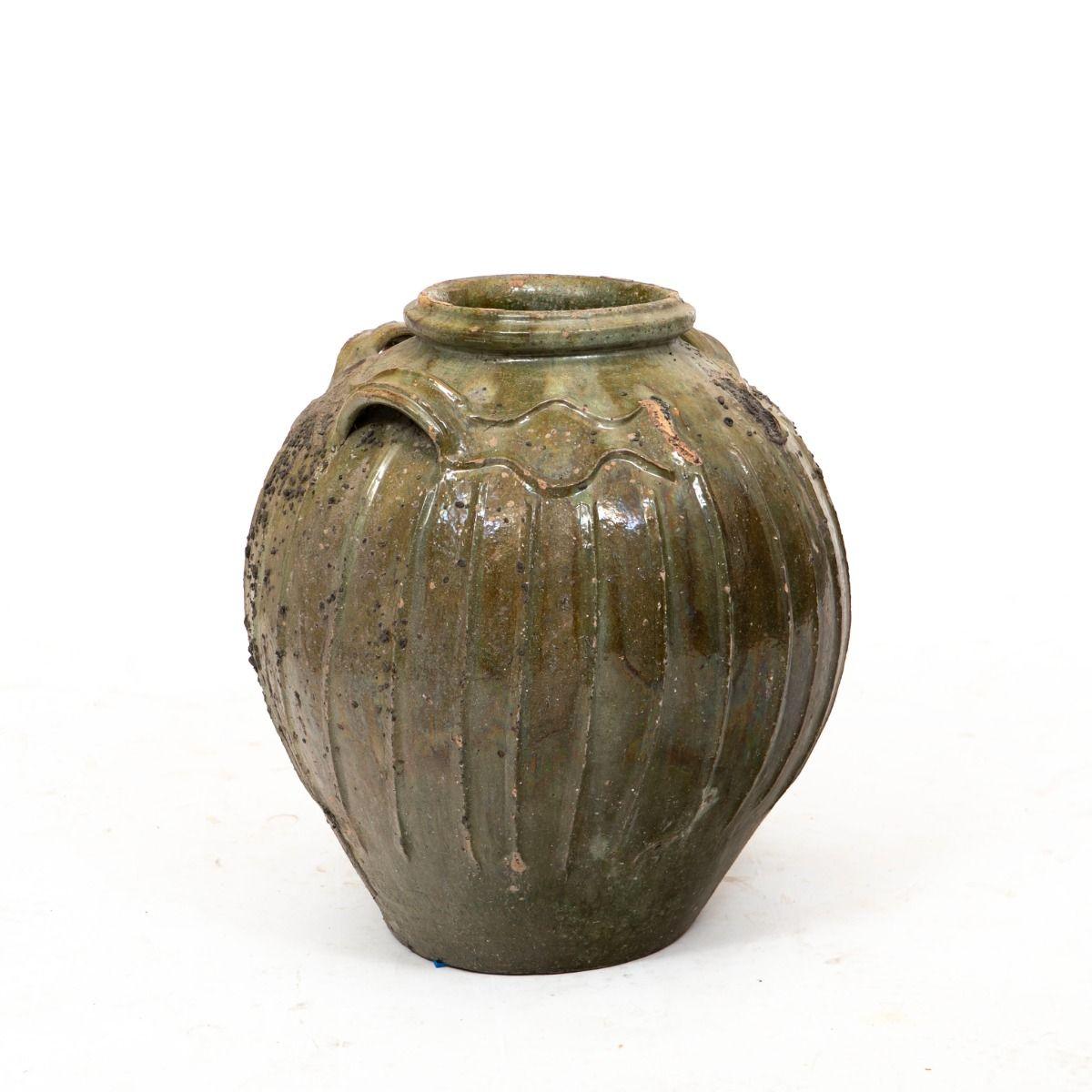 Chinese wine or oil jar from the Qing Dynasty (1750-1850).

Traditionally used for storage and transport, this jar is crafted in durable ceramic with vertical lines, a greenish glaze, and originally featured four integrated carrying handles—three of