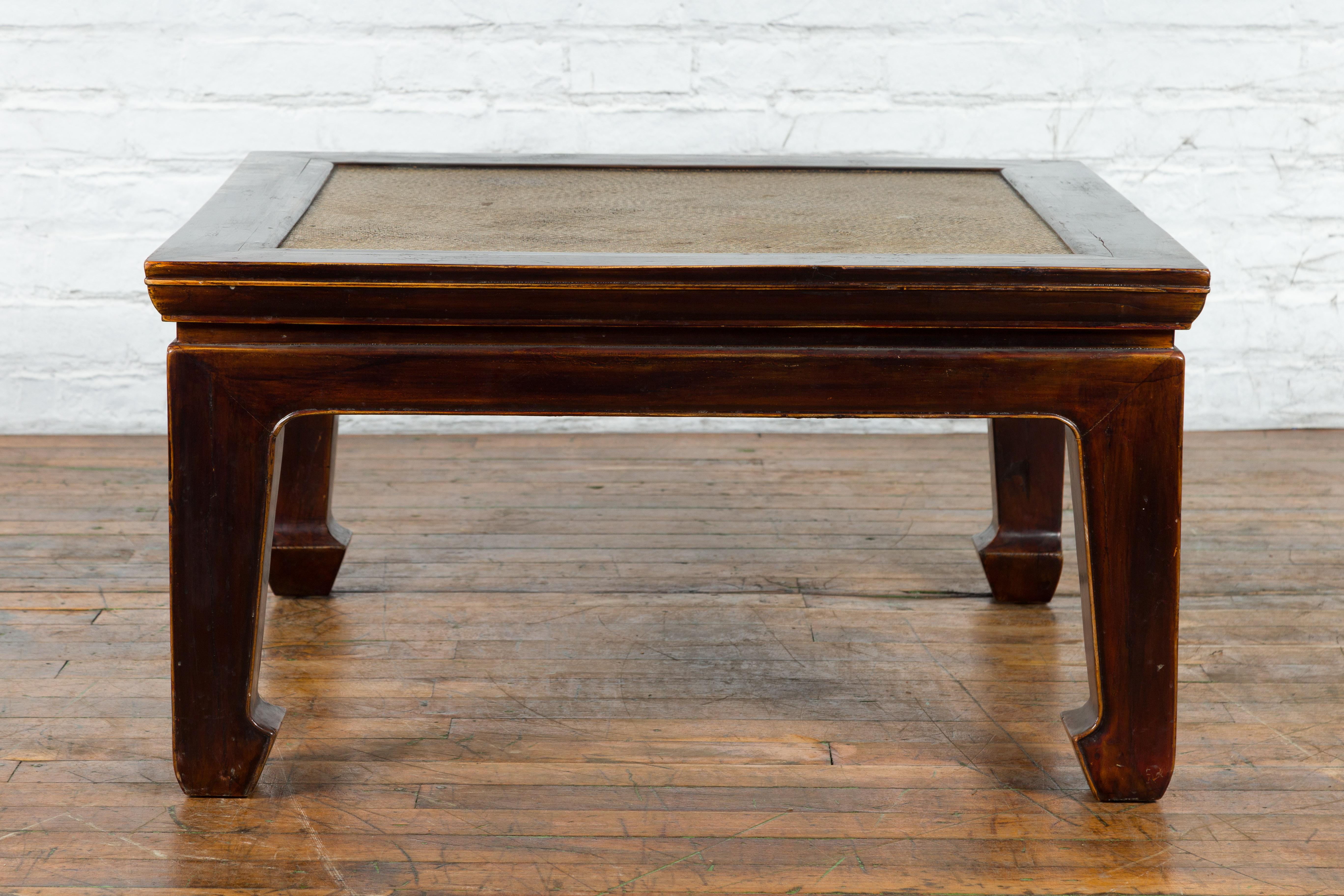 A Chinese Qing Dynasty period wooden coffee table from the late 19th, early 20th century, with woven rattan top, horse hoof legs and dark brown lacquer. Created in China during the Qing Dynasty period at the Turn of the Century, this wooden coffee