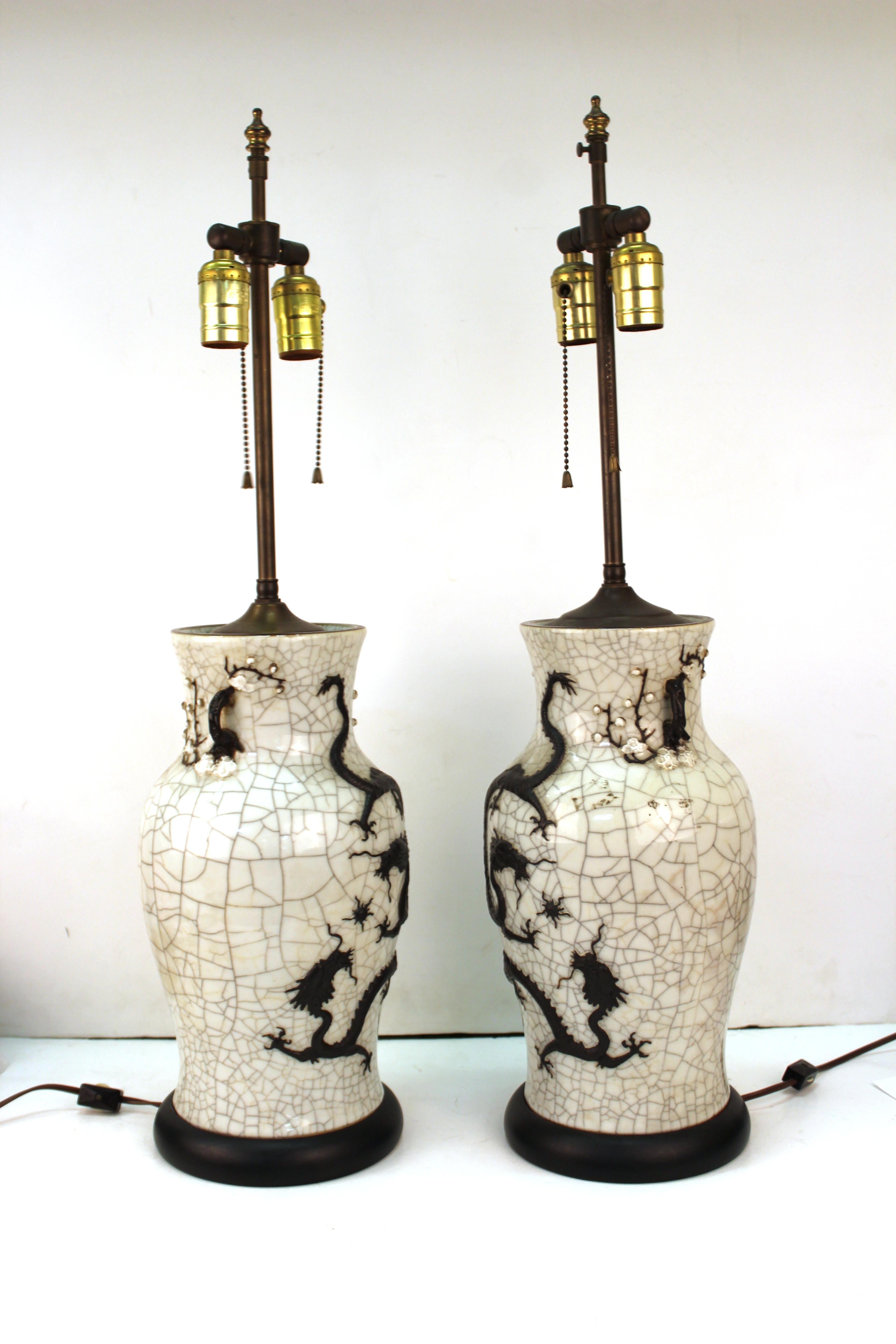 Chinese Qing dynasty pair of vases with crackle glaze and molded dragons. The pair is mounted on circular bases and transformed into table lamps. Made in the circa 1870s, the vases are in great antique condition with age-appropriate wear and use.