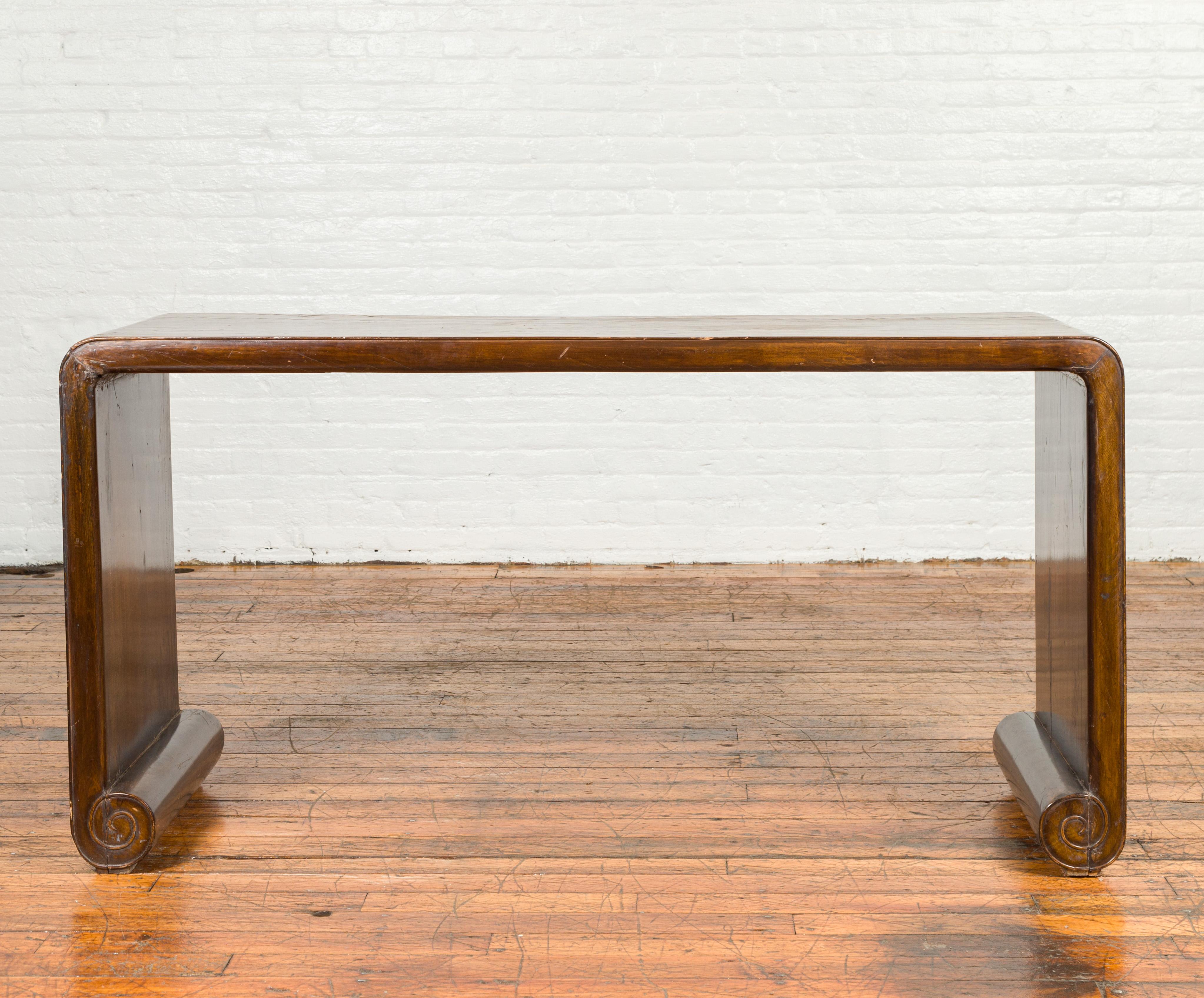 A Chinese Qing Dynasty period heavily distressed waterfall console table from the 19th century, with rollbar legs. Crafted in China during the 19th century this console table features a waterfall wooden frame with solid boards, boasting a nicely