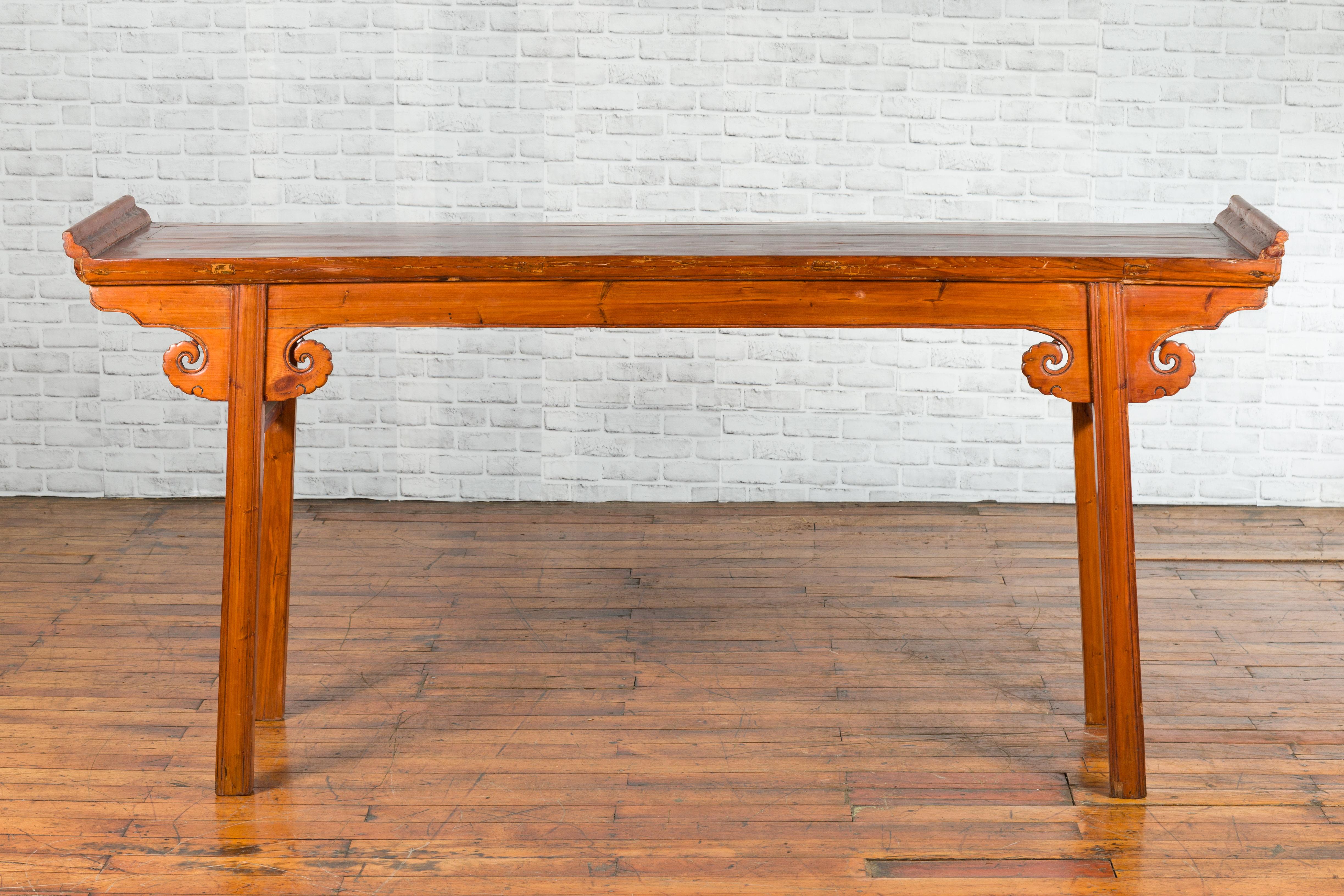 A Chinese Qing Dynasty period elmwood altar table from the 19th century with unusual patina and scrolling motifs. Created in China during the 19th century, this altar table attracts our attention with its vivid patina and elegant lines. A