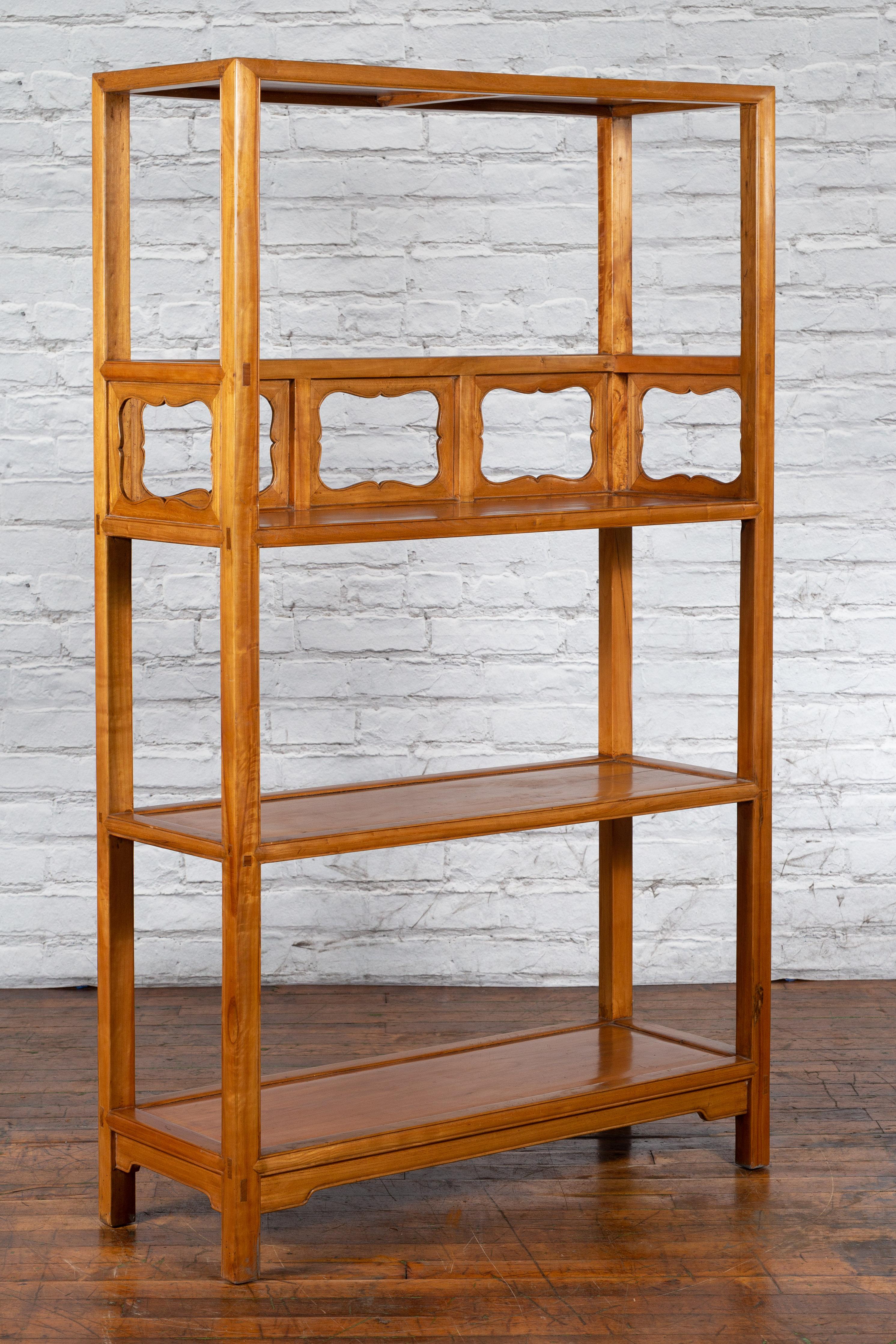 An antique Chinese Qing Dynasty elmwood bookcase from the 19th century, with three shelves and decorative carved panels. Created in China during the Qing Dynasty, this elmwood bookcase features an open structure made of three shelves adorned with