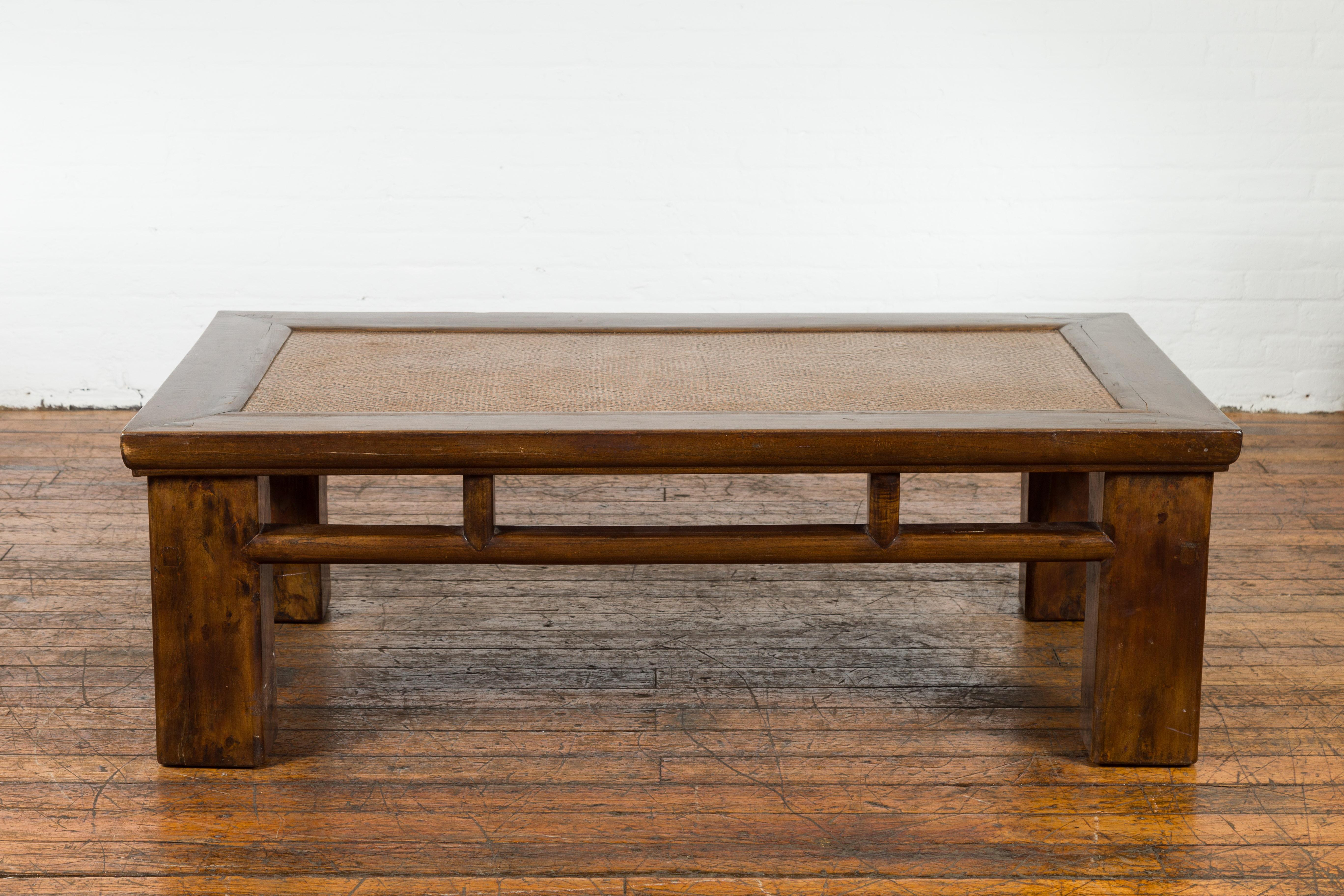 An antique Chinese Qing Dynasty period elm wood coffee table from the 19th century, with hand-woven rattan top inset, square legs, open apron and pillar strut motifs. Created in China, this low table was originally made from a cut down Lohan bed,