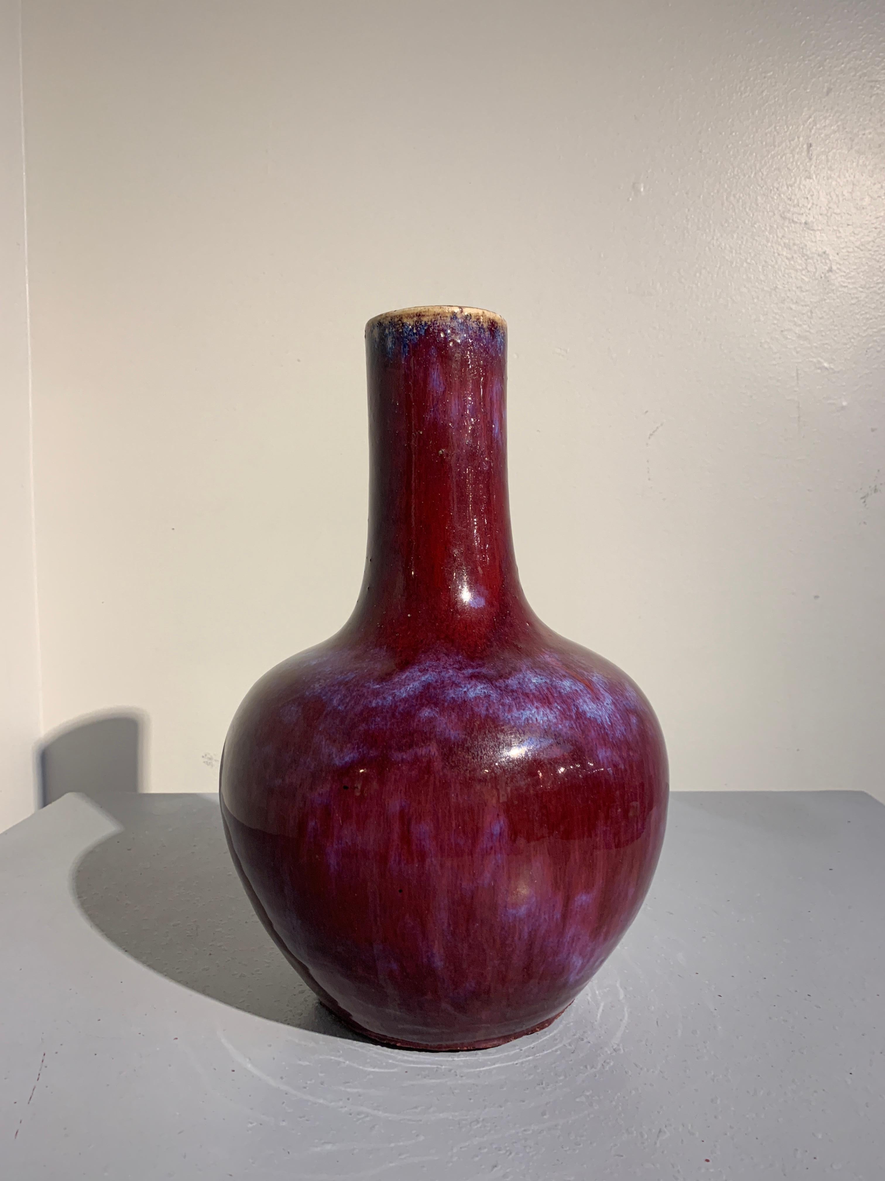 A gorgeous Chinese monochrome red flambé glazed bottle vase, called a tianqiuping, Qing Dynasty, late 19th century. 

The voluptuous body of the vase of globular form, rising to broad shoulders and a tall stick neck. The vase is covered in a