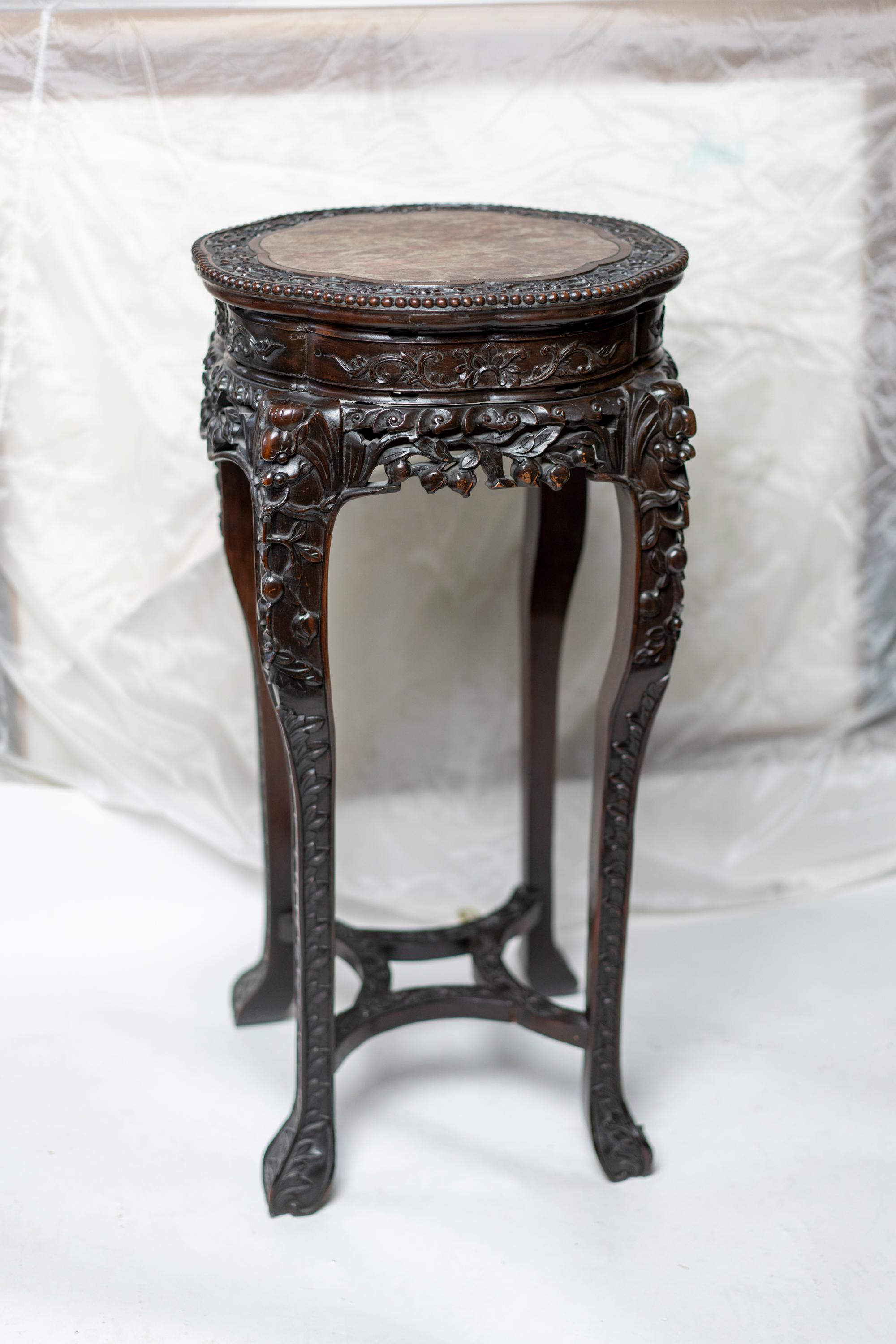 Chinese Qing dynasty intricately carved hard wood pedestal with a scalloped edged marble inset top.
  