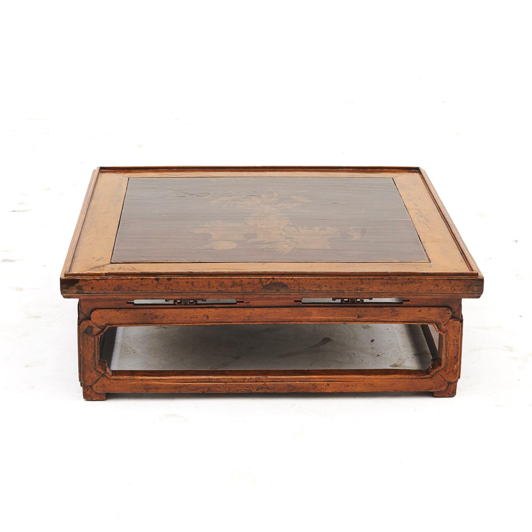 A Chinese Qing dynasty Kang table from Manchuria, China.
This low table features a rectangular top in warmly colored lacquer with raised edge, inset in a darker finish decorated with chinoiserie.
Original condition with a beautiful natural