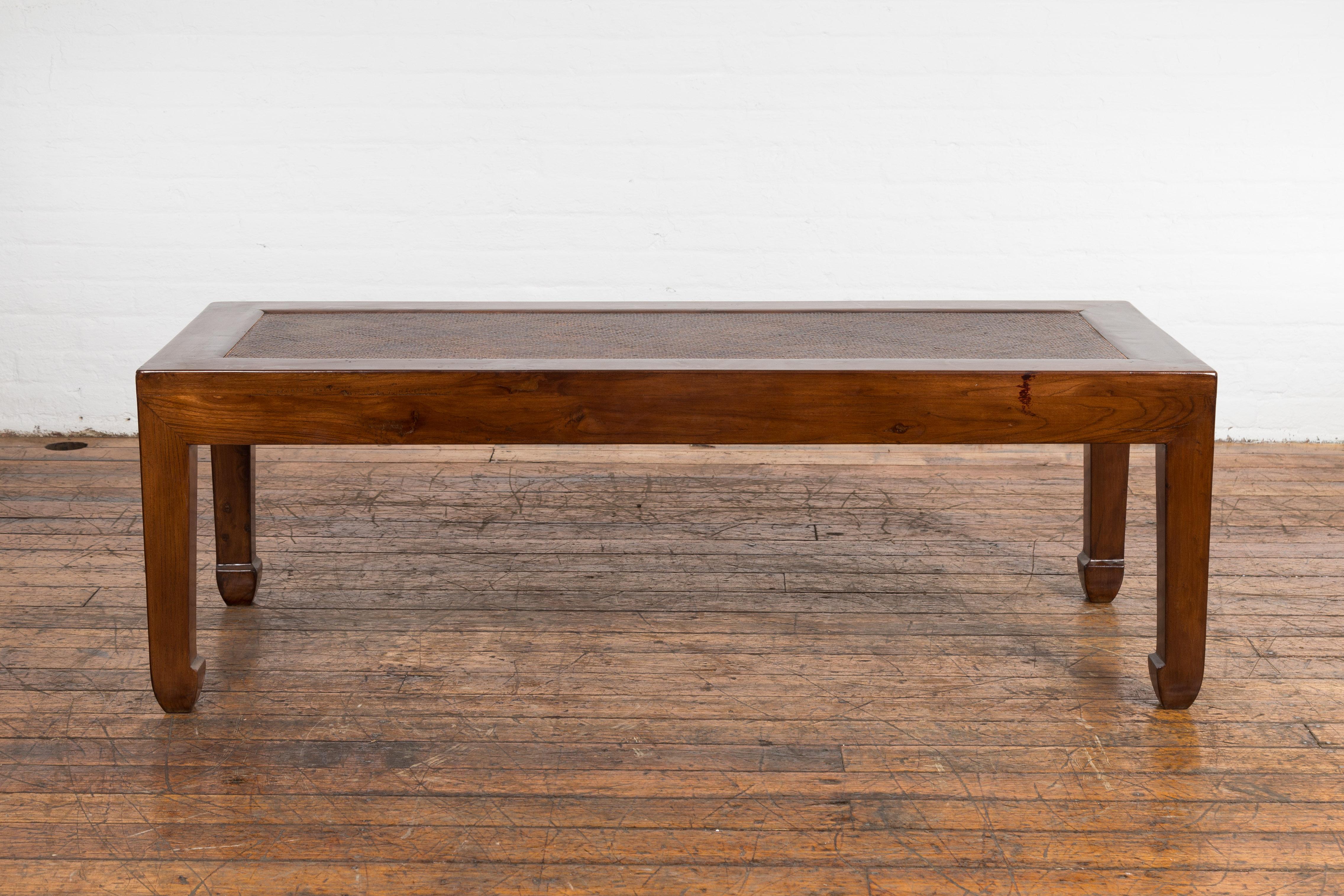 A Chinese late Qing Dynasty period low Kang coffee table from the early 20th century with inset rattan top and horse hoof feet. Delve into the rich history of Chinese furniture design with this low Kang coffee table from the late Qing Dynasty