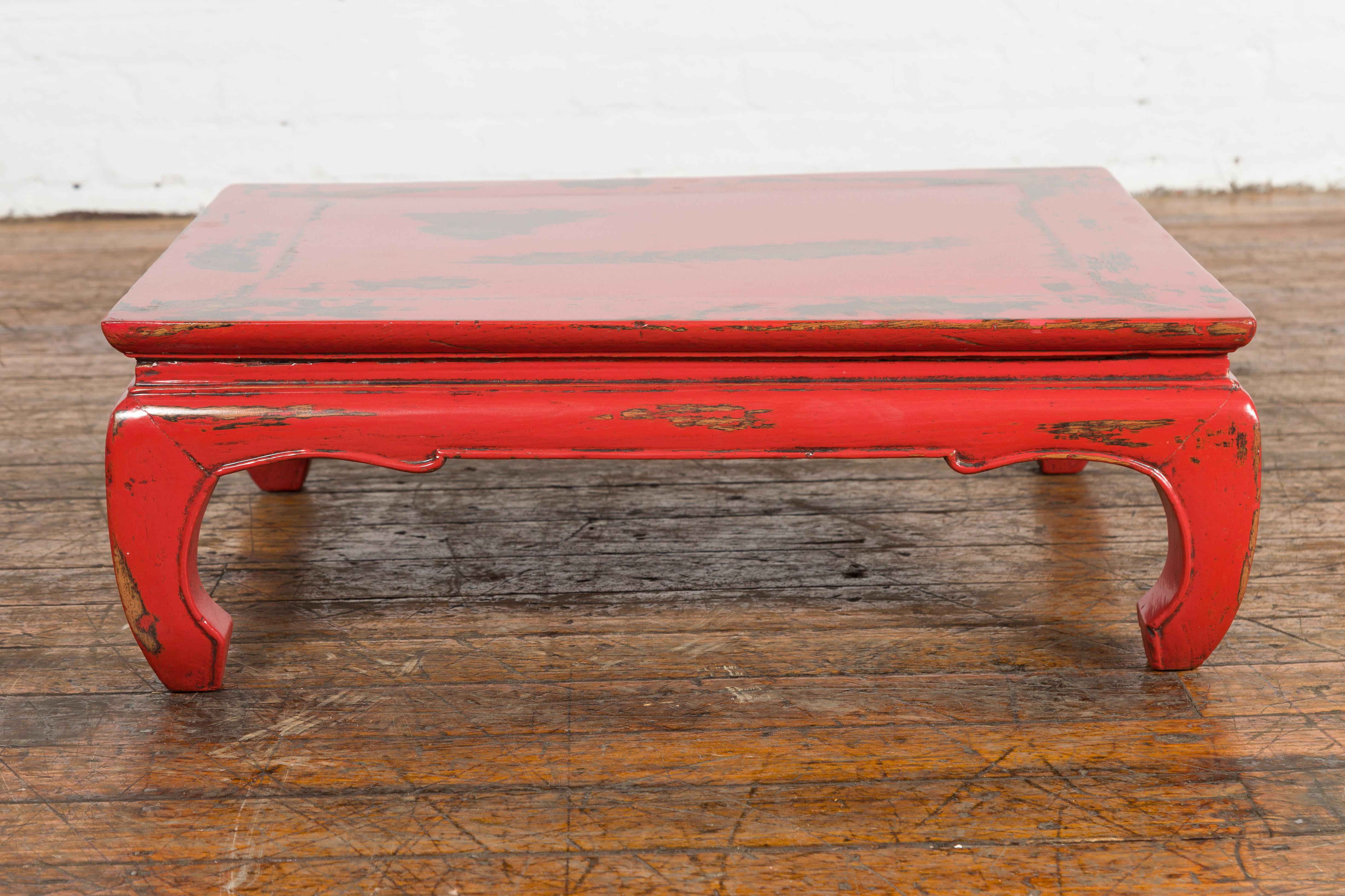 A Chinese Qing Dynasty period low Kang table from the 19th century, with chow legs, carved apron and restored with custom red distressed lacquer. Created in China during the Qing Dynasty period in the 19th century, this low kang table will make for