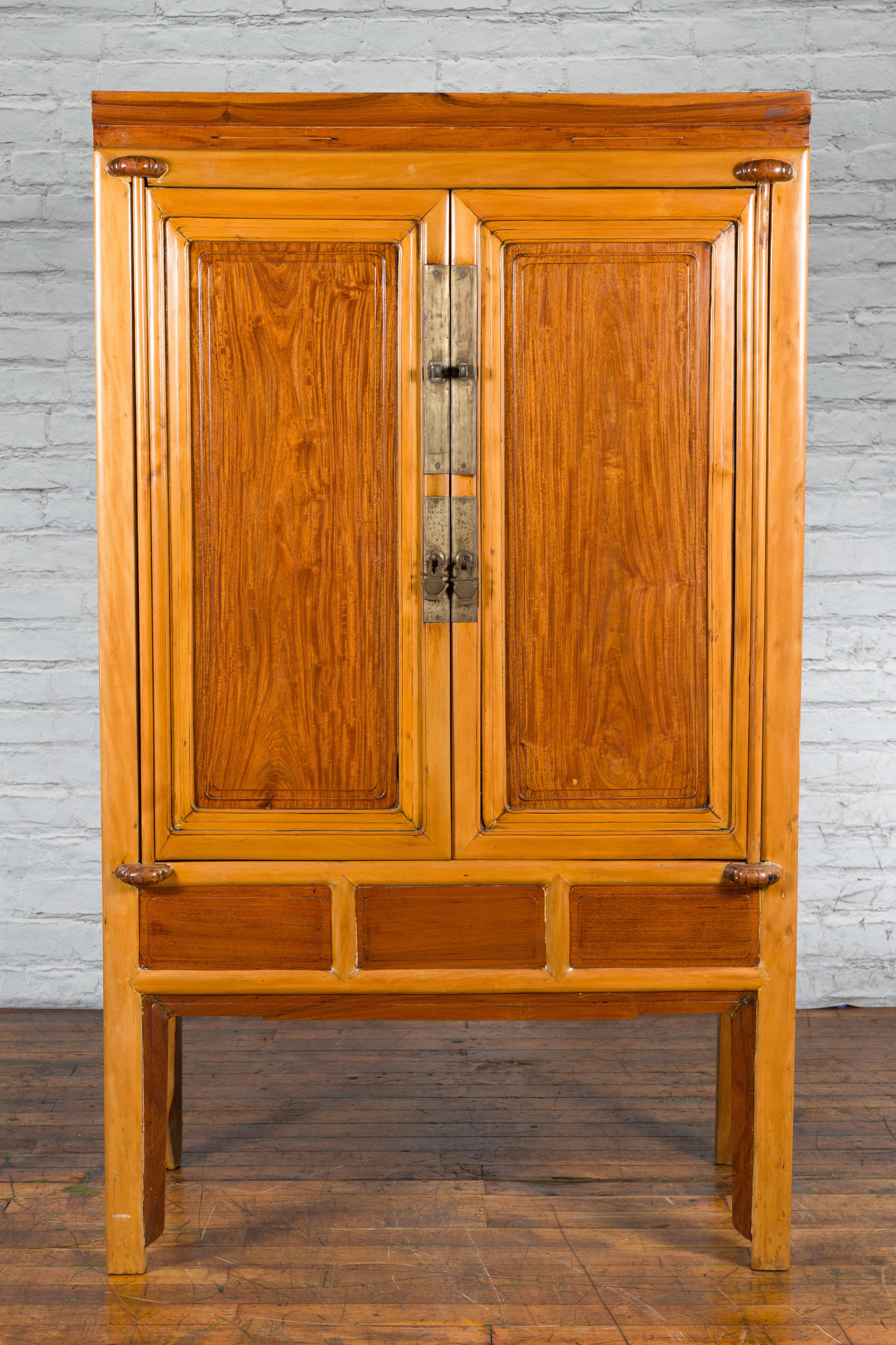 A Chinese Qing Dynasty period two-toned ningbo cypress and rosewood cabinet from the 19th century, with brass hardware. Created in China during the Qing Dynasty in the 19th century, this tall cabinet features a linear silhouette perfectly