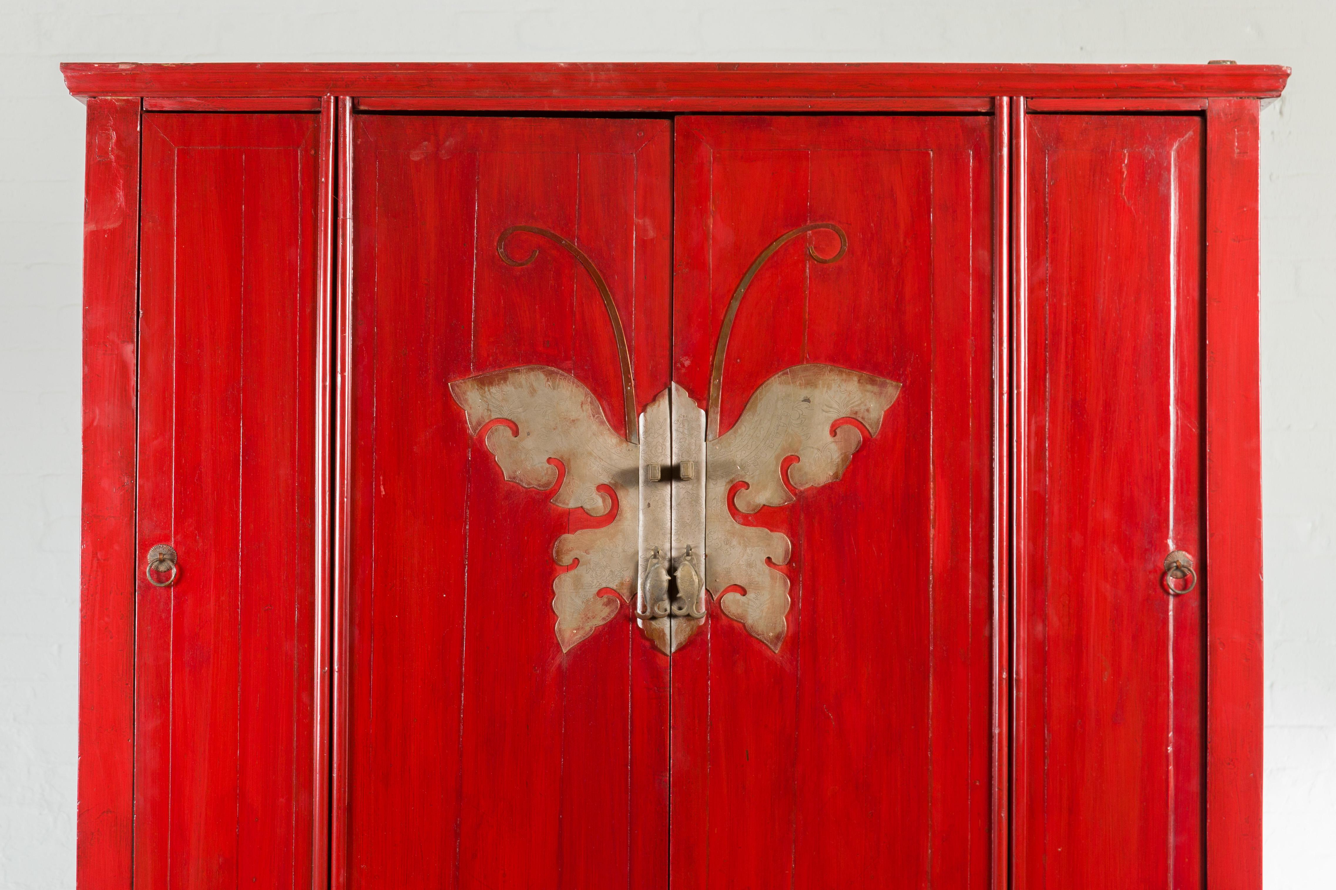 A Chinese Qing Dynasty Ningbo red lacquered four-door wedding cabinet from the 19th century, with butterfly hardware. Created in Eastern China during the Qing Dynasty, this wedding cabinet captures our attention with its stunning red lacquered