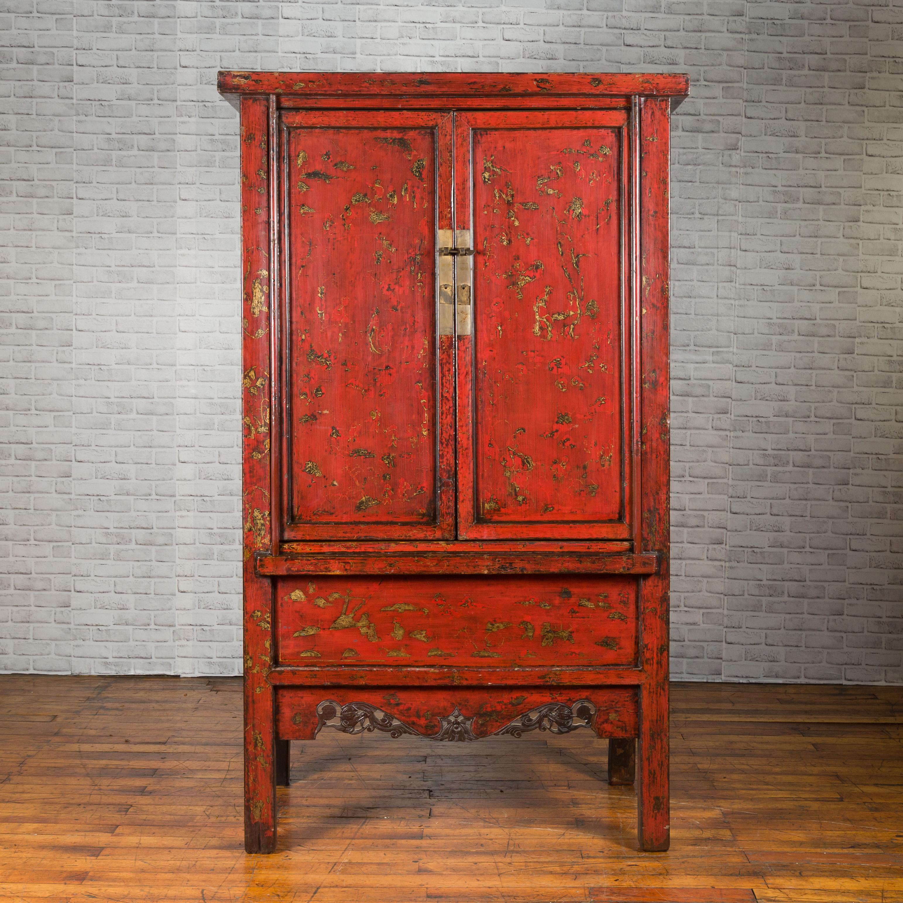 A Chinese Qing Dynasty style red lacquer cabinet from the 20th century, with gilded chinoiserie motifs and carved apron. Created in China during the Qing Dynasty, this cabinet features a red lacquered finish accented with traces of a delicate gilt
