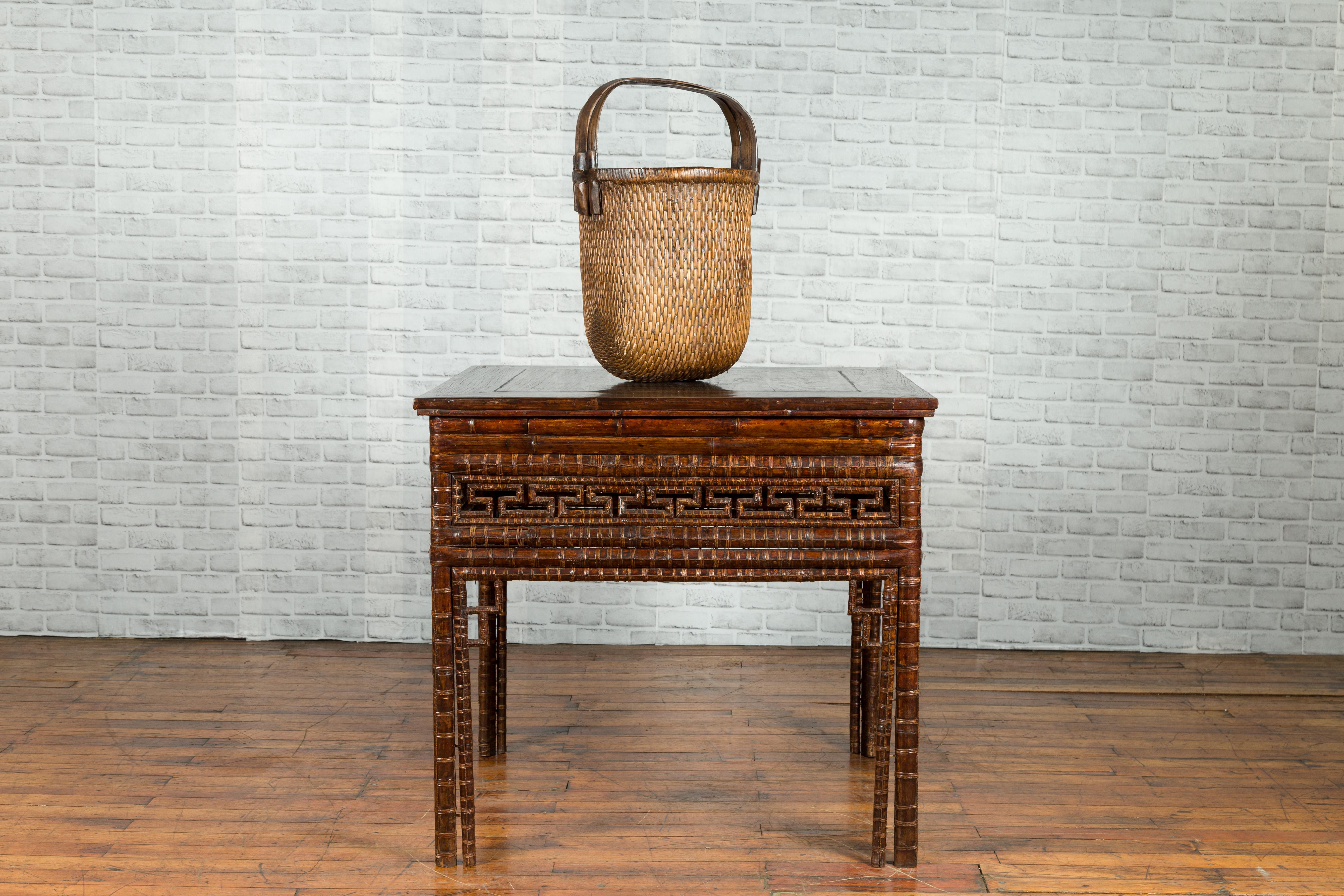 A Chinese Qing Dynasty period bamboo hall table from the 19th century, with fretwork motifs. Created in China during the Qing Dynasty, this hall table features a square top with central board, sitting above an elegant bamboo base. The apron, adorned