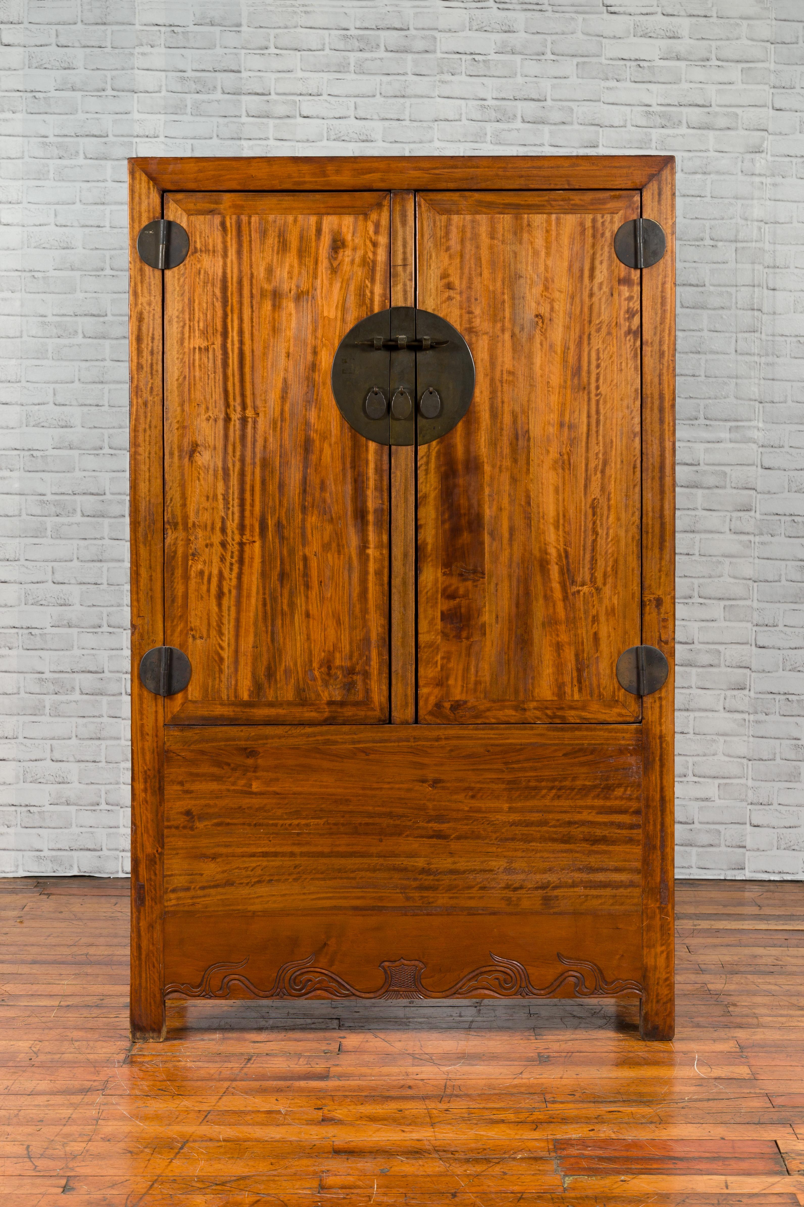 A Chinese Qing Dynasty period cabinet from the 19th century, with traditional hardware, two hidden drawers and a removable panel. Created in China during the Qing Dynasty, this wooden cabinet features two doors fitted with a large round medallion,