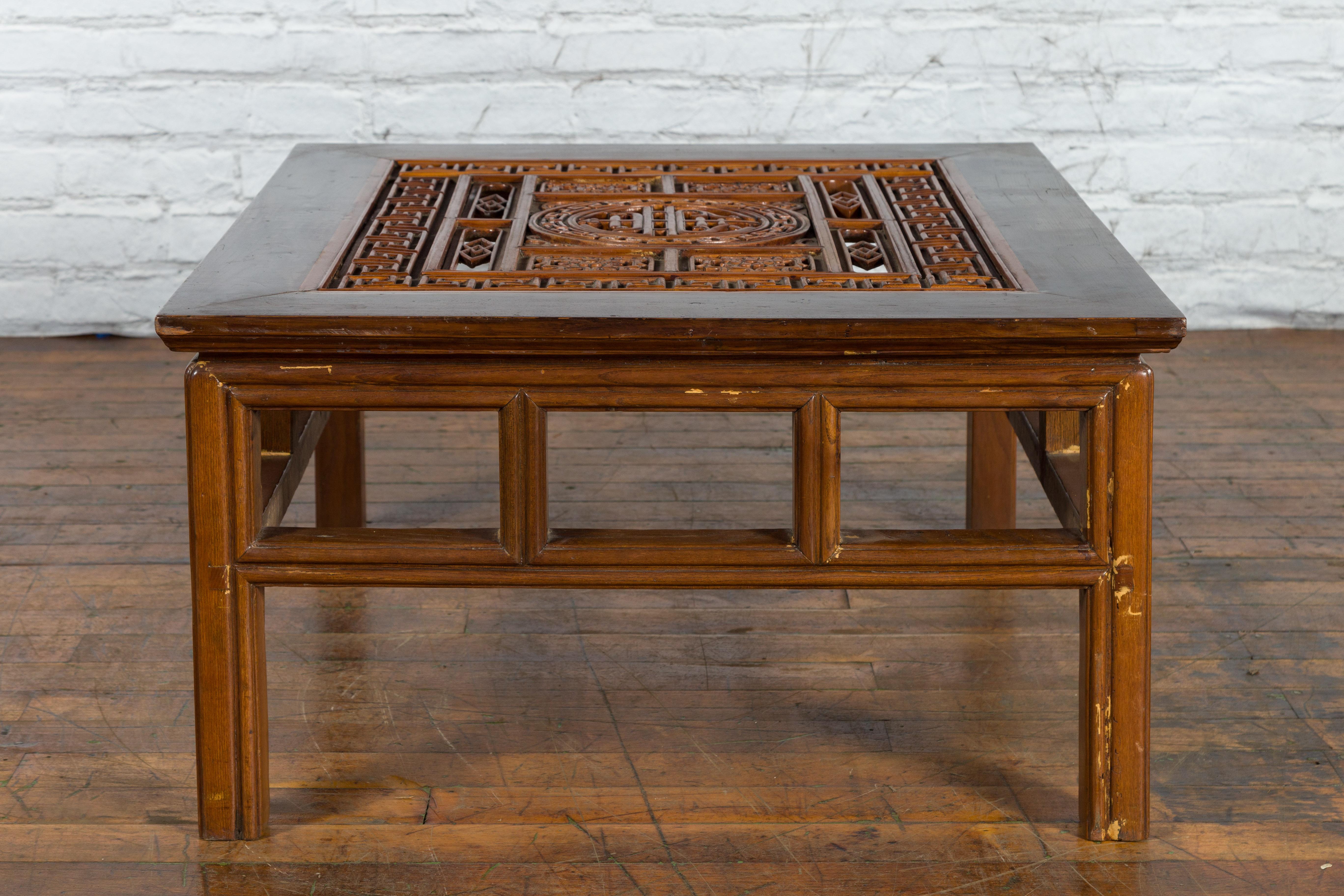 A Chinese Qing Dynasty period wooden coffee table from the 19th century with carved fretwork top, pierced apron and straight legs. Created in China during the Qing Dynasty in the 19th century, this wooden coffee table attracts immediately our