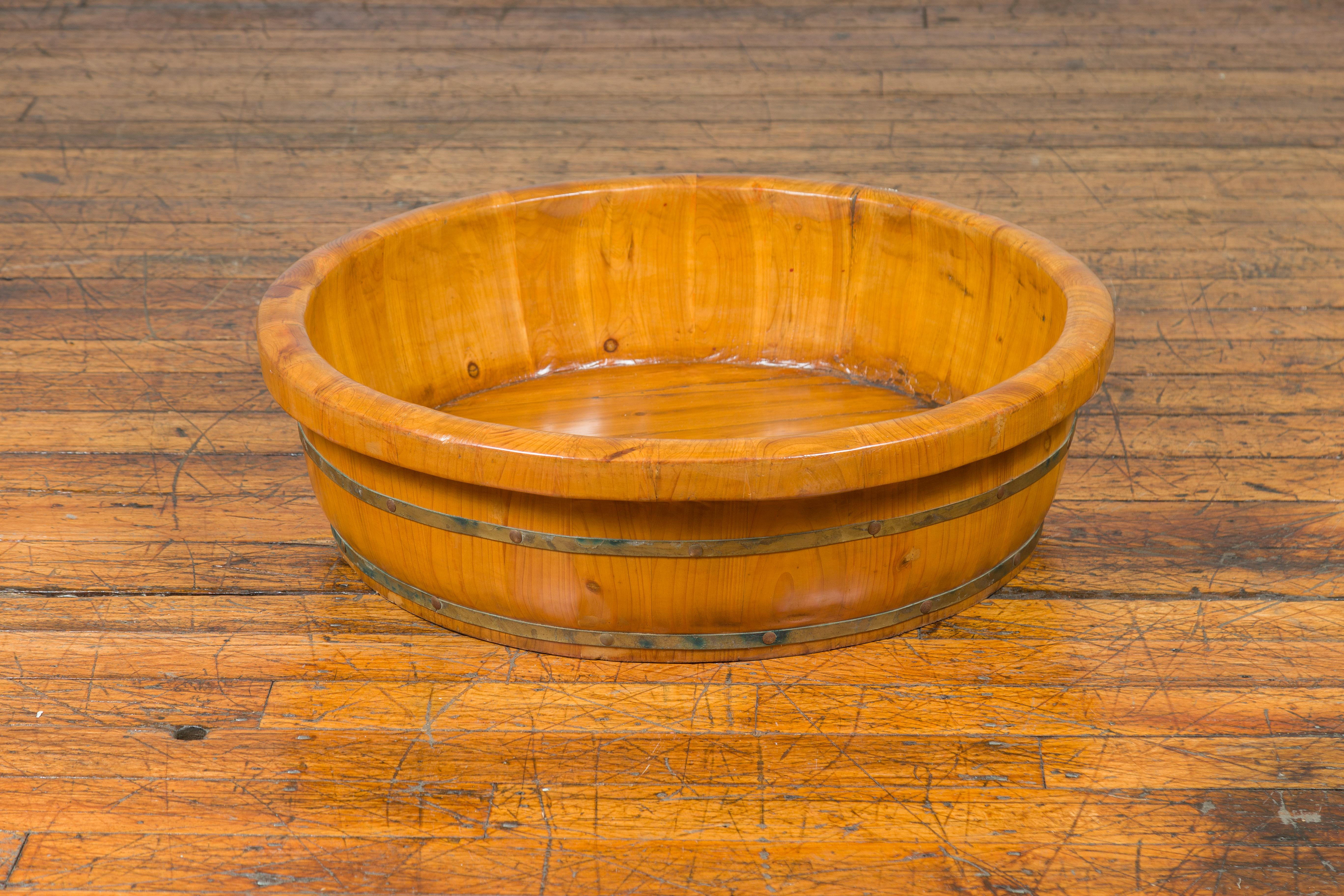 A large Qing dynasty period elm rice tray from the 19th century with brass braces. This Qing dynasty elm rice tray is a testament to the enduring craftsmanship of 19th-century China. Its circular form, crowned with a subtle lip, is reinforced by