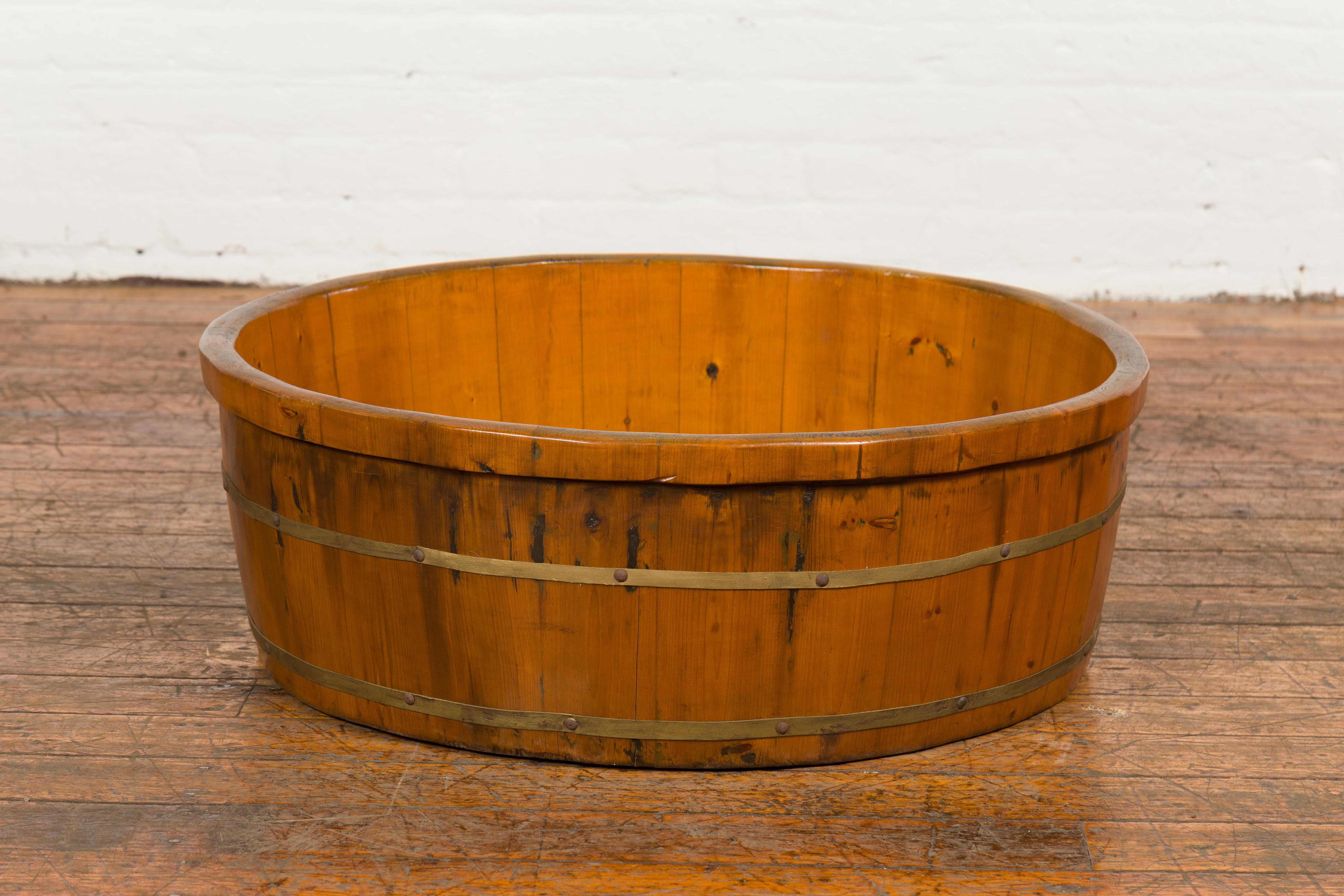 A large Chinese Qing Dynasty period elm wood rice tray from the 19th century with brass braces and honey color. Crafted in China during the Qing dynasty period in the 19th century, this elm rice tray features a circular body topped with a thin lip